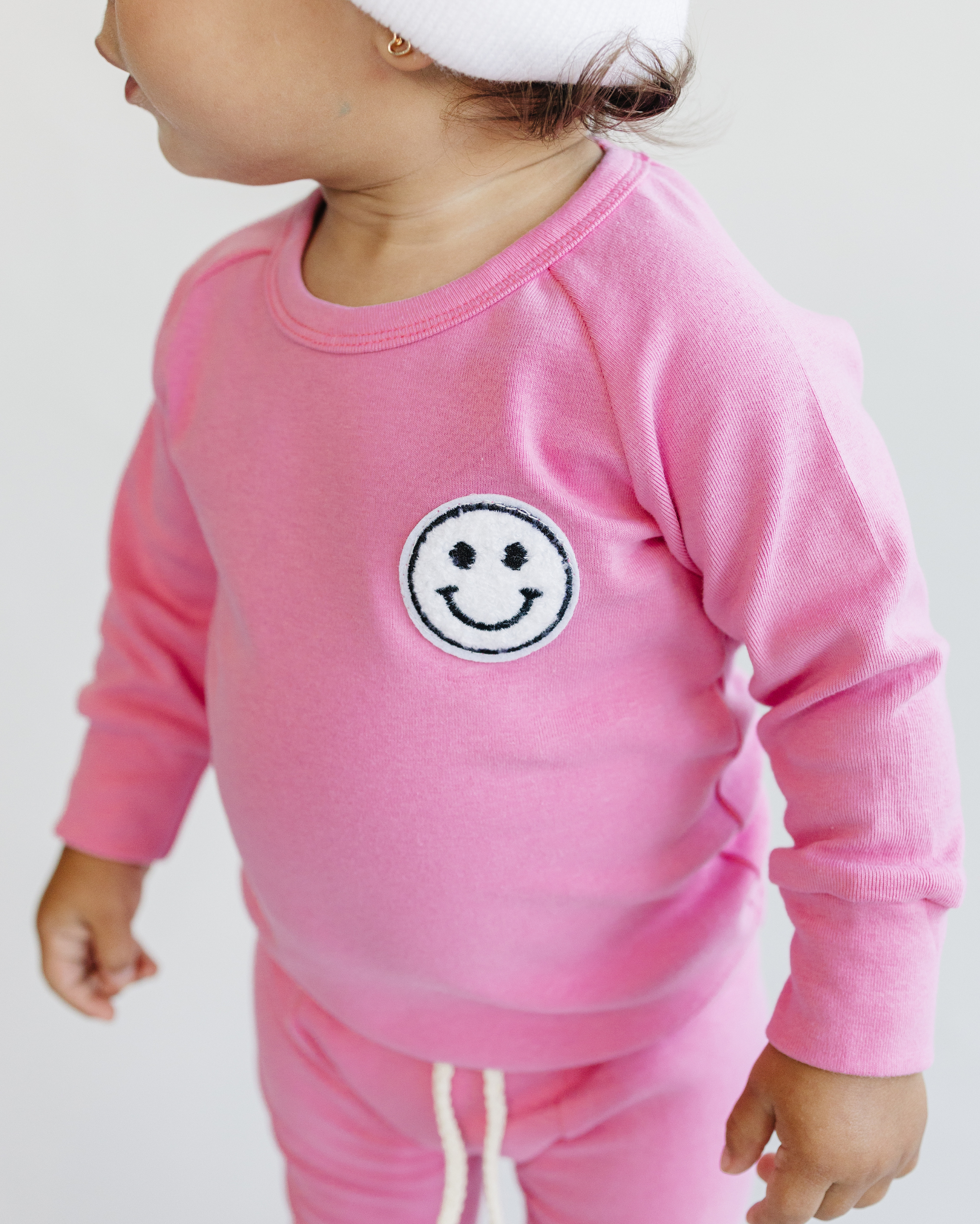 Toddler girl wearing lounge set smiley bubble gum in vibrant pink with a smiley patch.