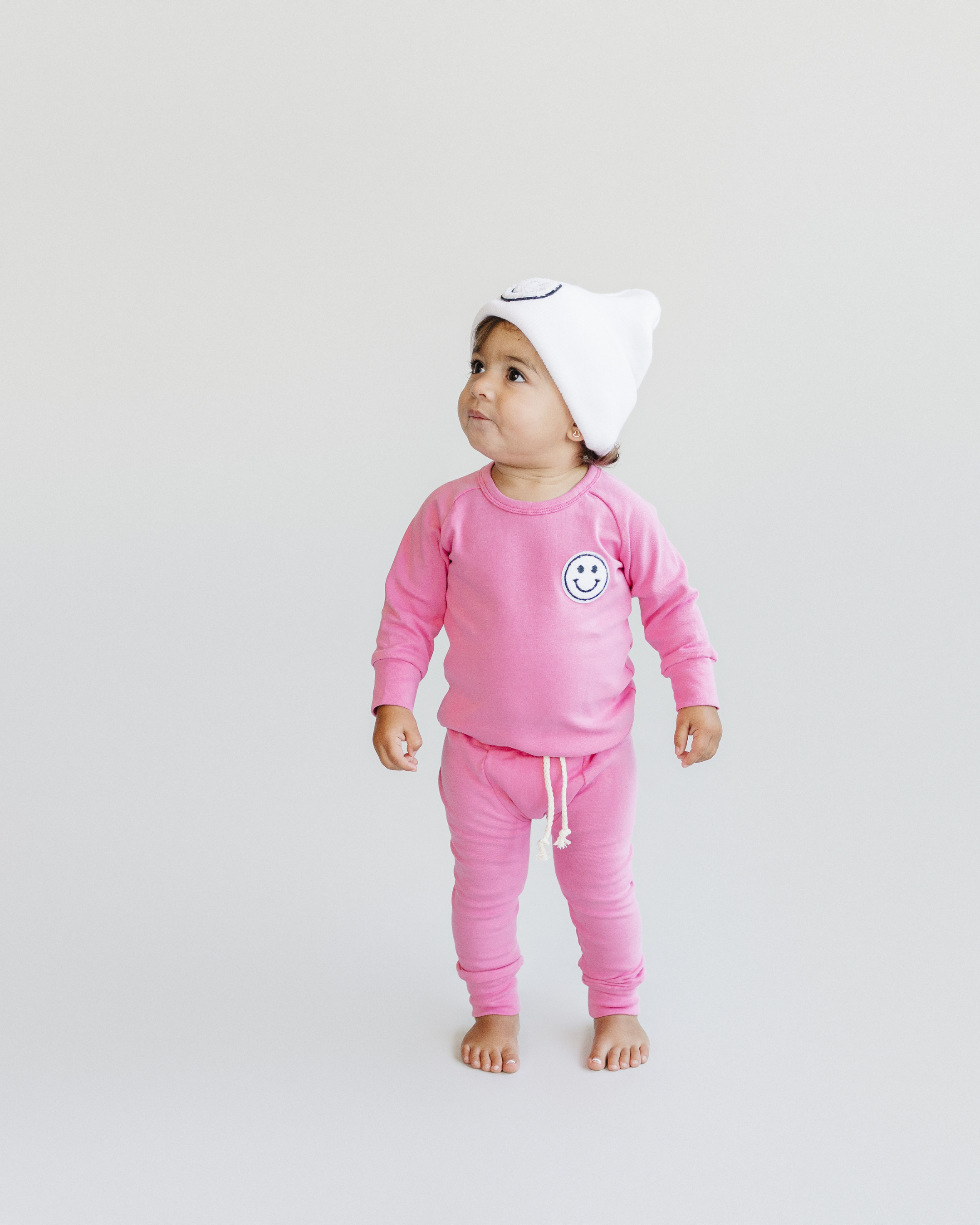 Cute toddler in lounge set smiley bubble gum, featuring soft pink top and pants with smiley patch.