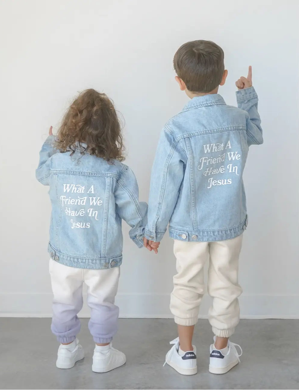 Two kids wearing What a Friend in Jesus kids denim jacket, showcasing faith and style with a meaningful design.