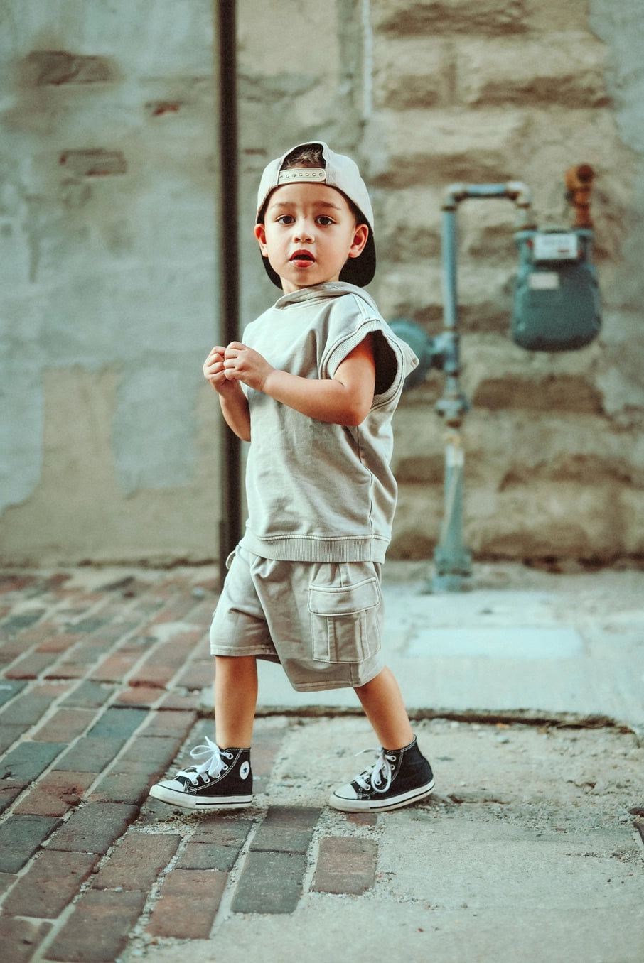 Tan acid wash sleeveless hoodie worn by a child, showcasing vintage streetwear style in a casual outdoor setting.