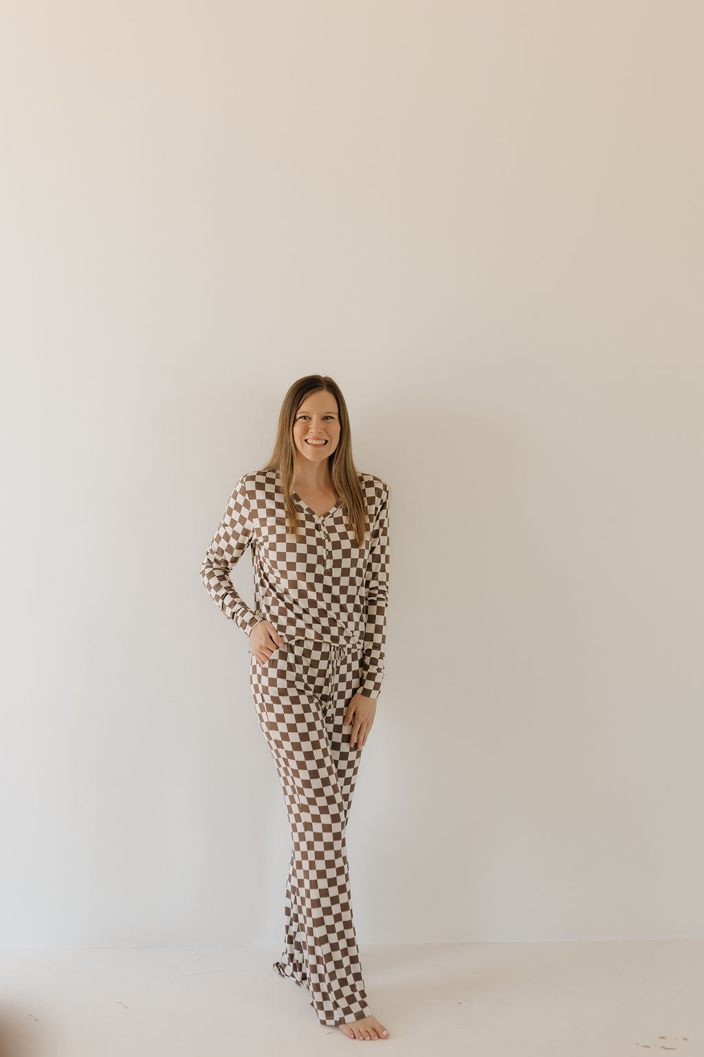 Womens bamboo pajama dutton set in brown and cream checkerboard print, model smiling, standing against a plain background.