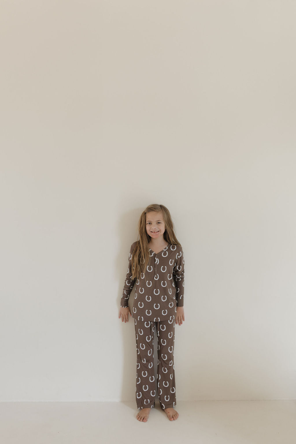 Youth flare bamboo pajamas giddy up in brown horseshoe print worn by a girl, ideal for cozy lounging.