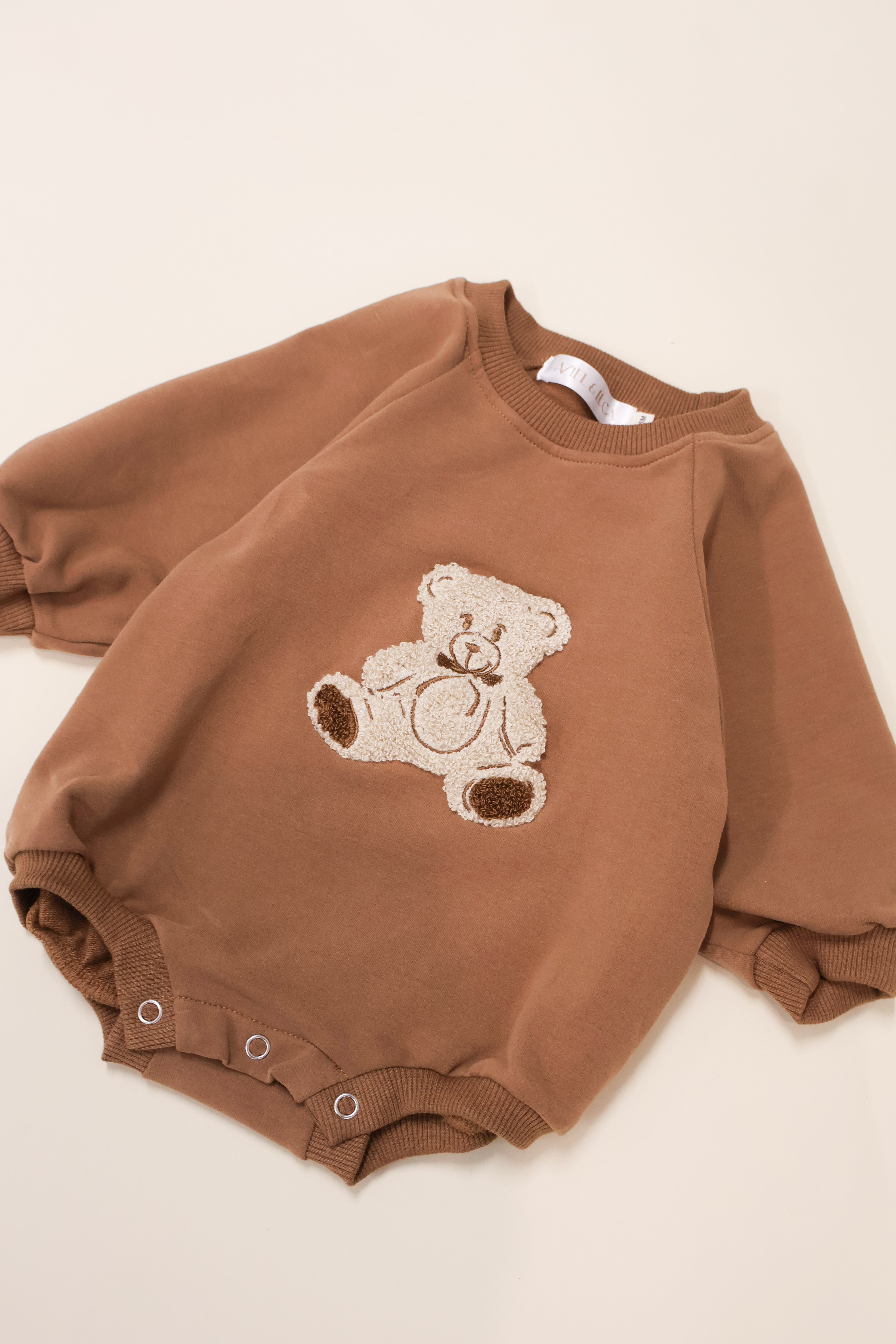 Bear Bubble Romper in soft brown French terry with teddy bear embroidery and snap closures for easy dressing.
