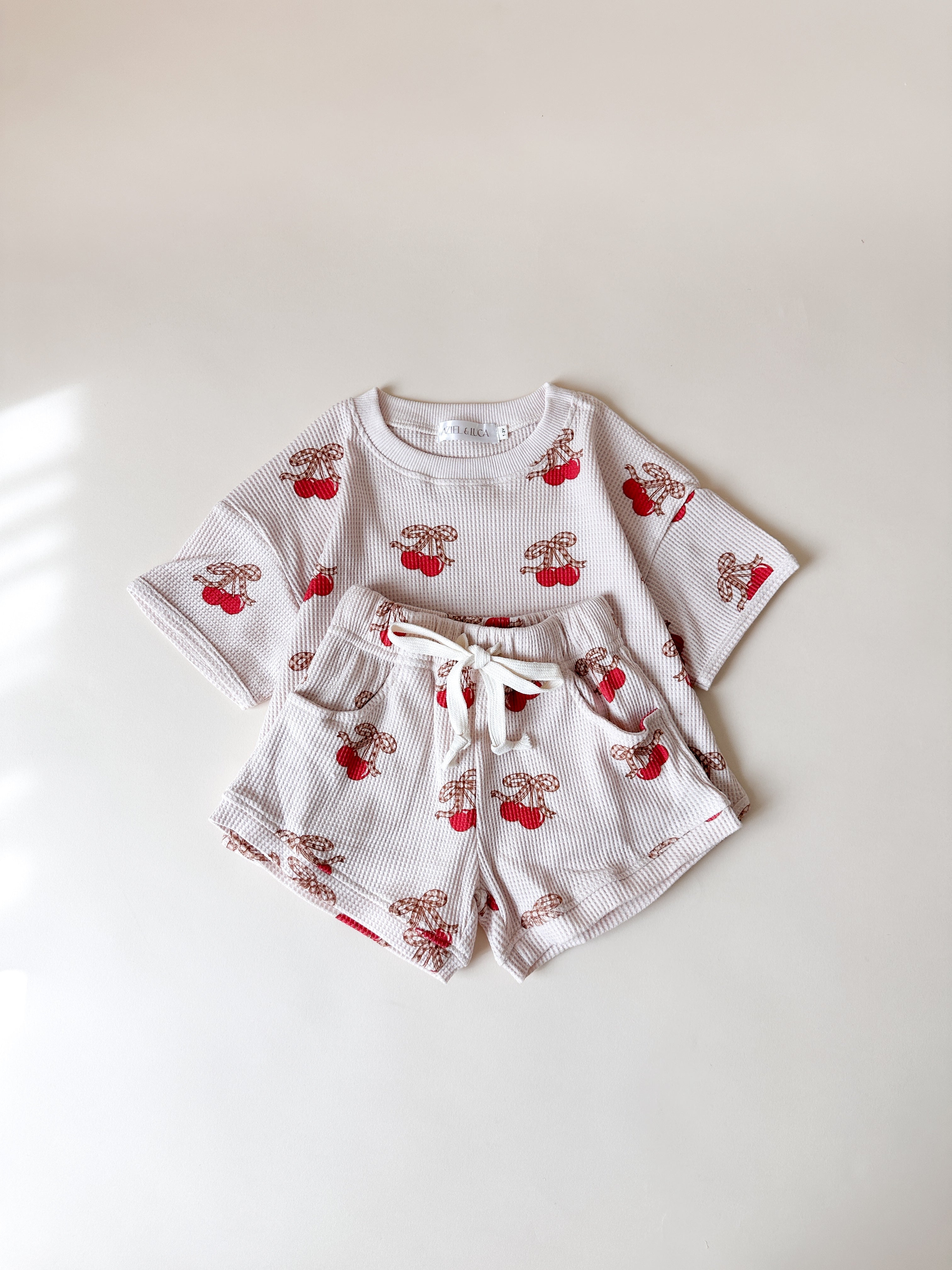 Printed waffle sets kids featuring a playful cherry print tee and shorts for summer fun.