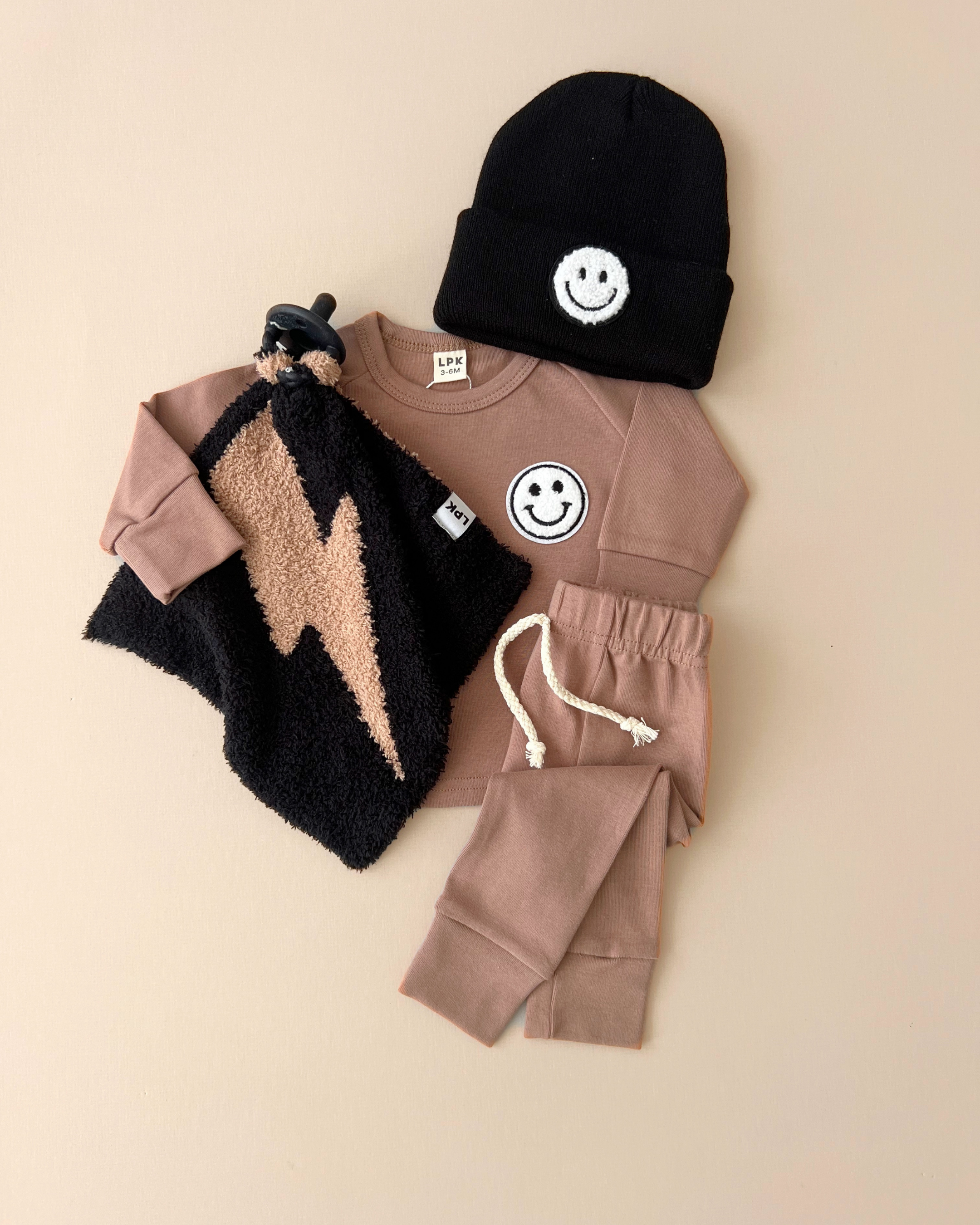 Lounge set smiley mocha for kids featuring a tee, shorts, hat, and cozy blanket with smiley and lightning design.