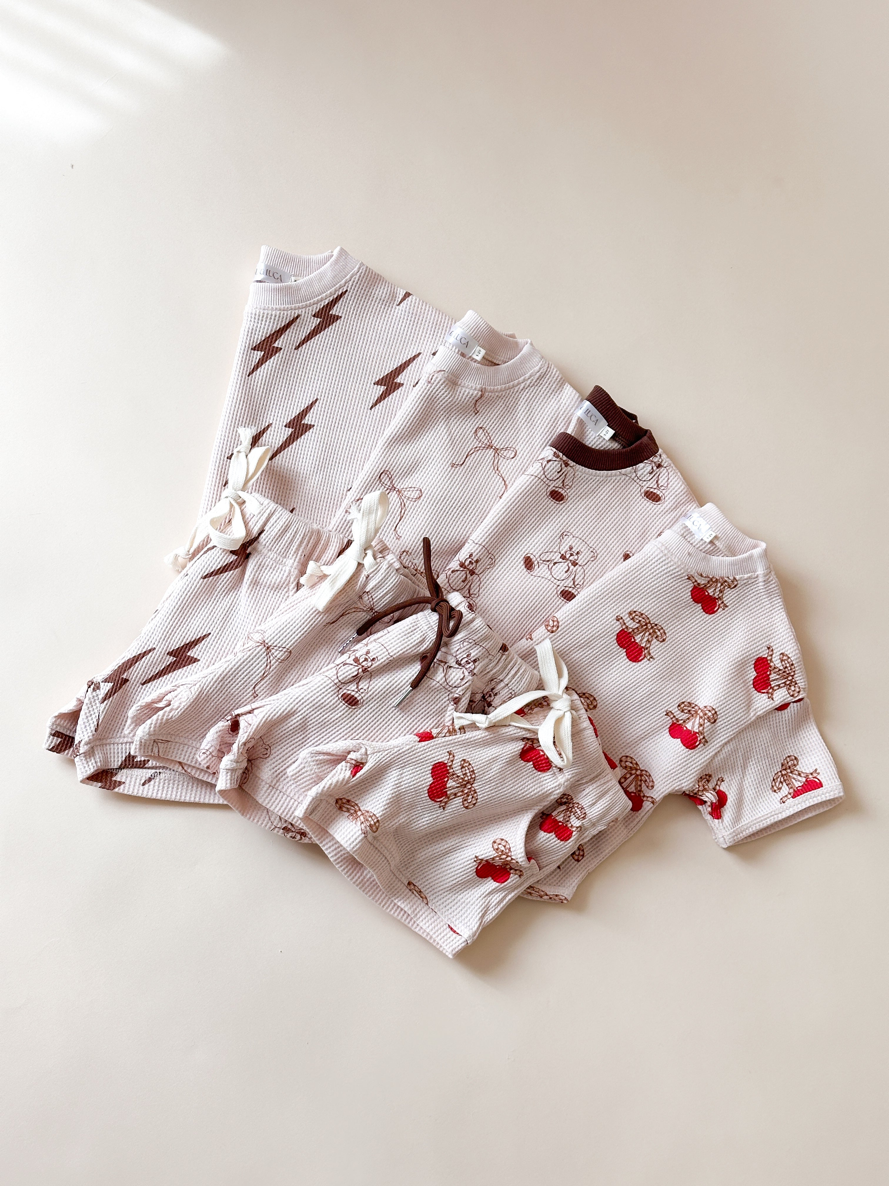Printed waffle sets for kids featuring playful designs: Bolt, Bow, Cherry, and Bear in soft fabrics.