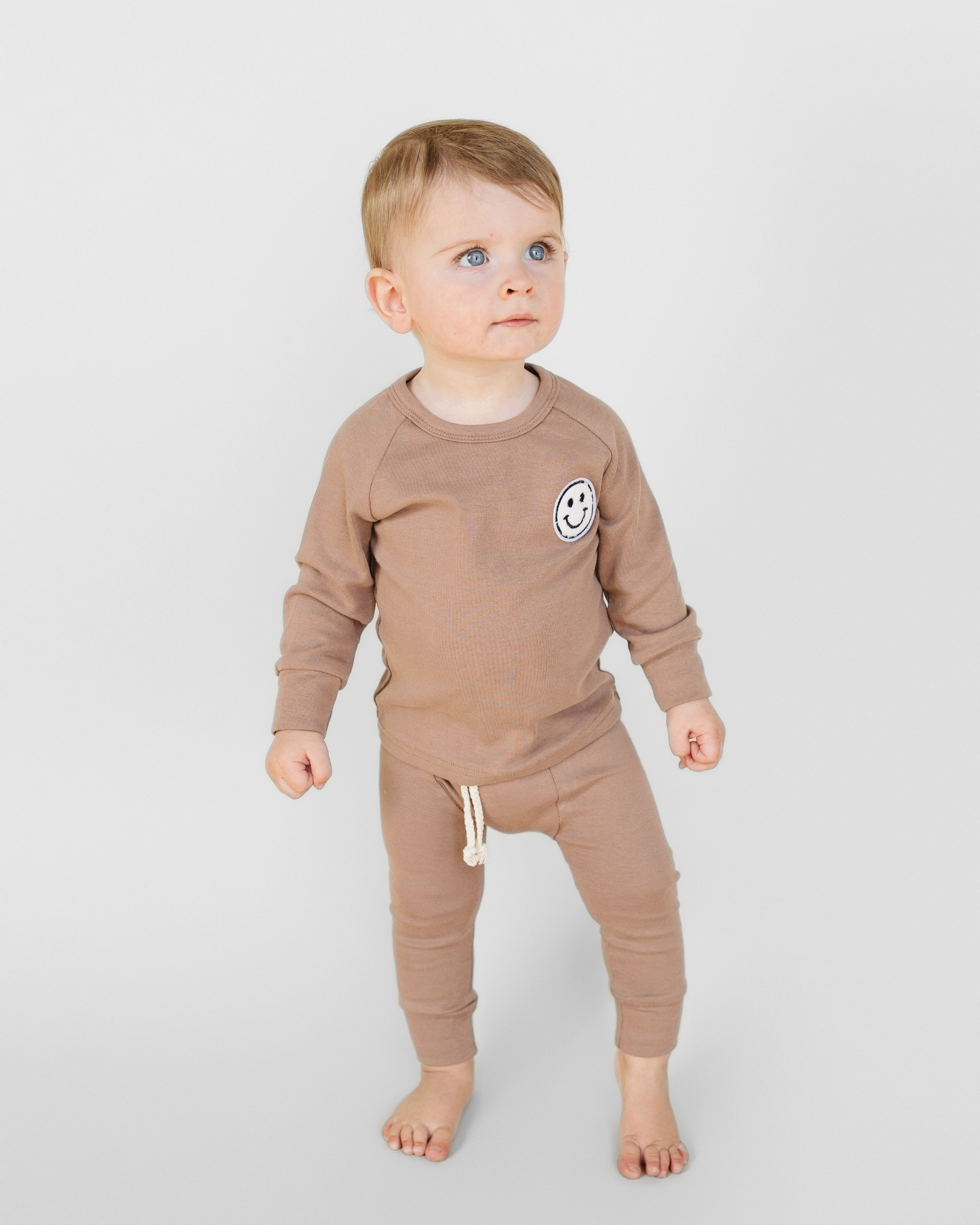 Toddler wearing lounge set smiley mocha featuring a relaxed tee and comfy pants with a smiley patch.