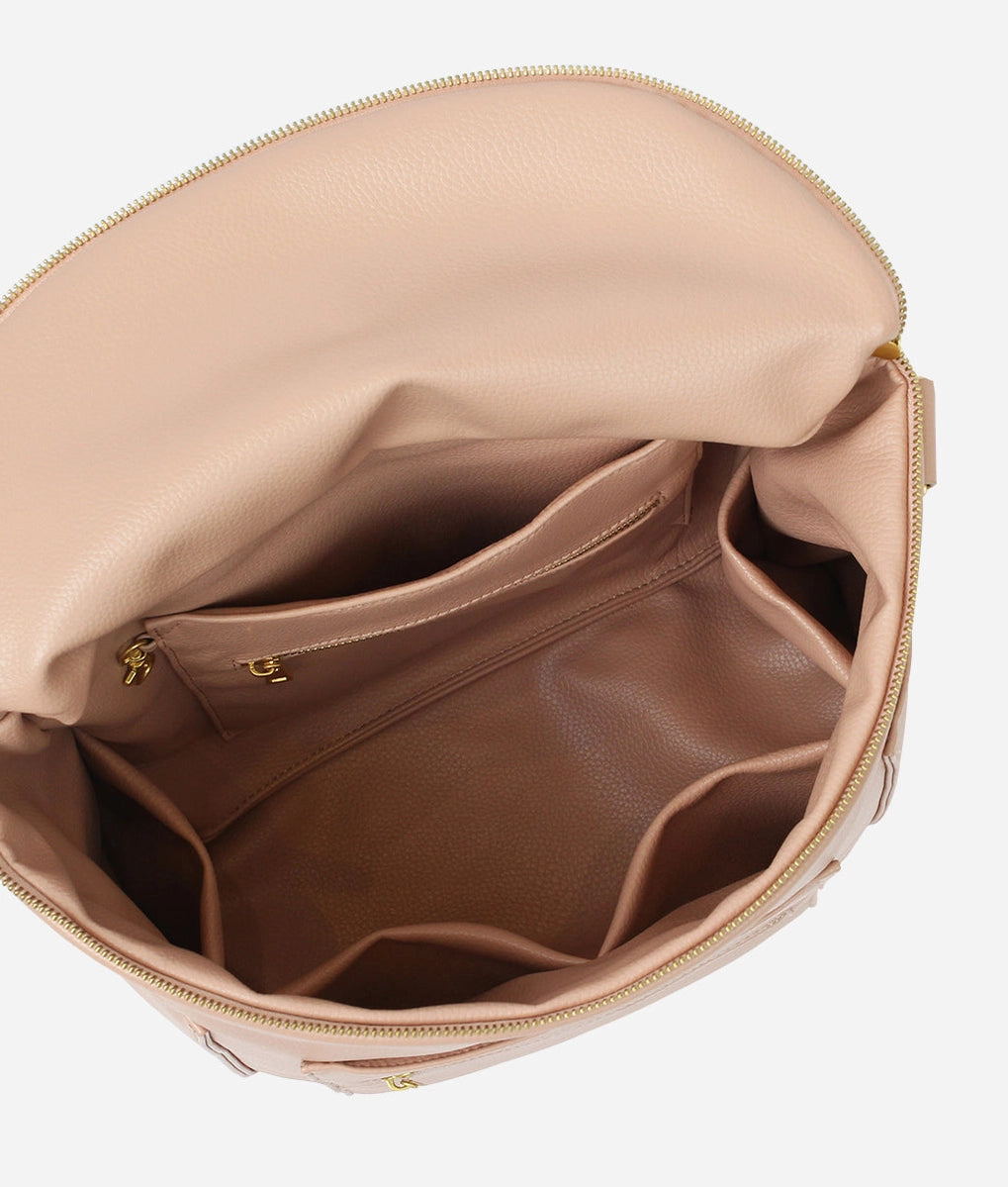 Interior view of Original Diaper Bag Backpack showing organized pockets and soft blush faux leather lining.