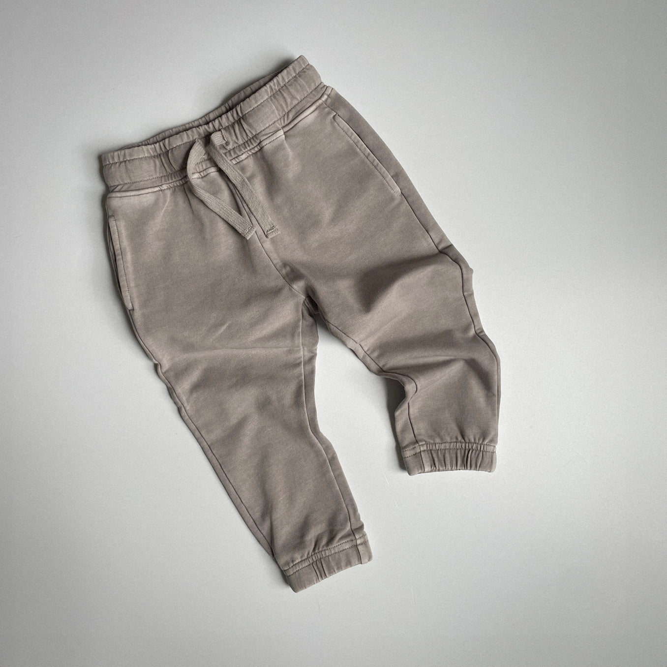 Tan acid wash joggers for kids, featuring a relaxed fit, elastic waistband, and cuffed ankles, perfect for comfort and style.