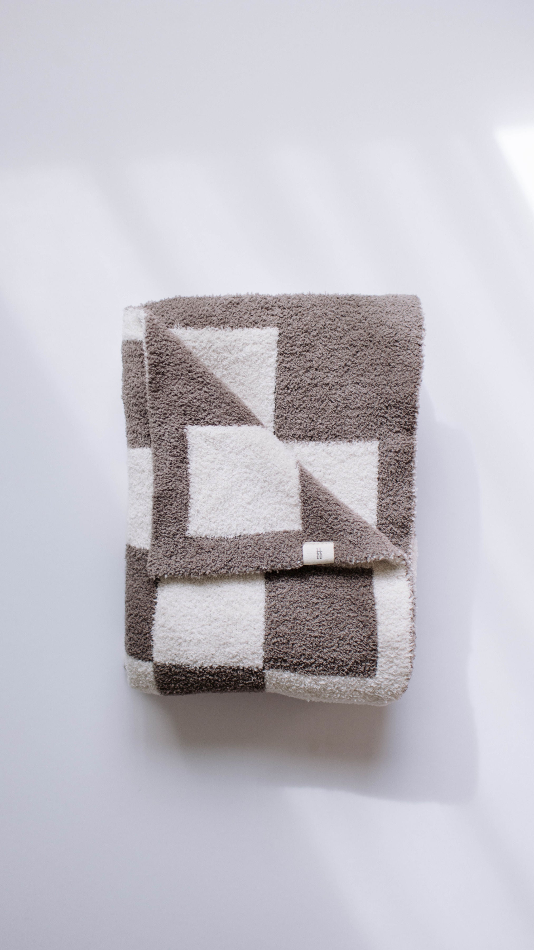 Cozy plush mushroom checkerboard blanket folded on a light background, perfect for modern nursery decor.