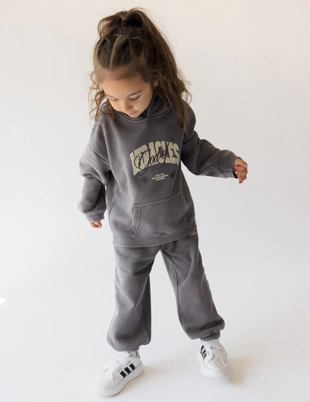 A young girl wearing a cozy God of Miracles kids hoodie with a stylish design and comfortable fit.