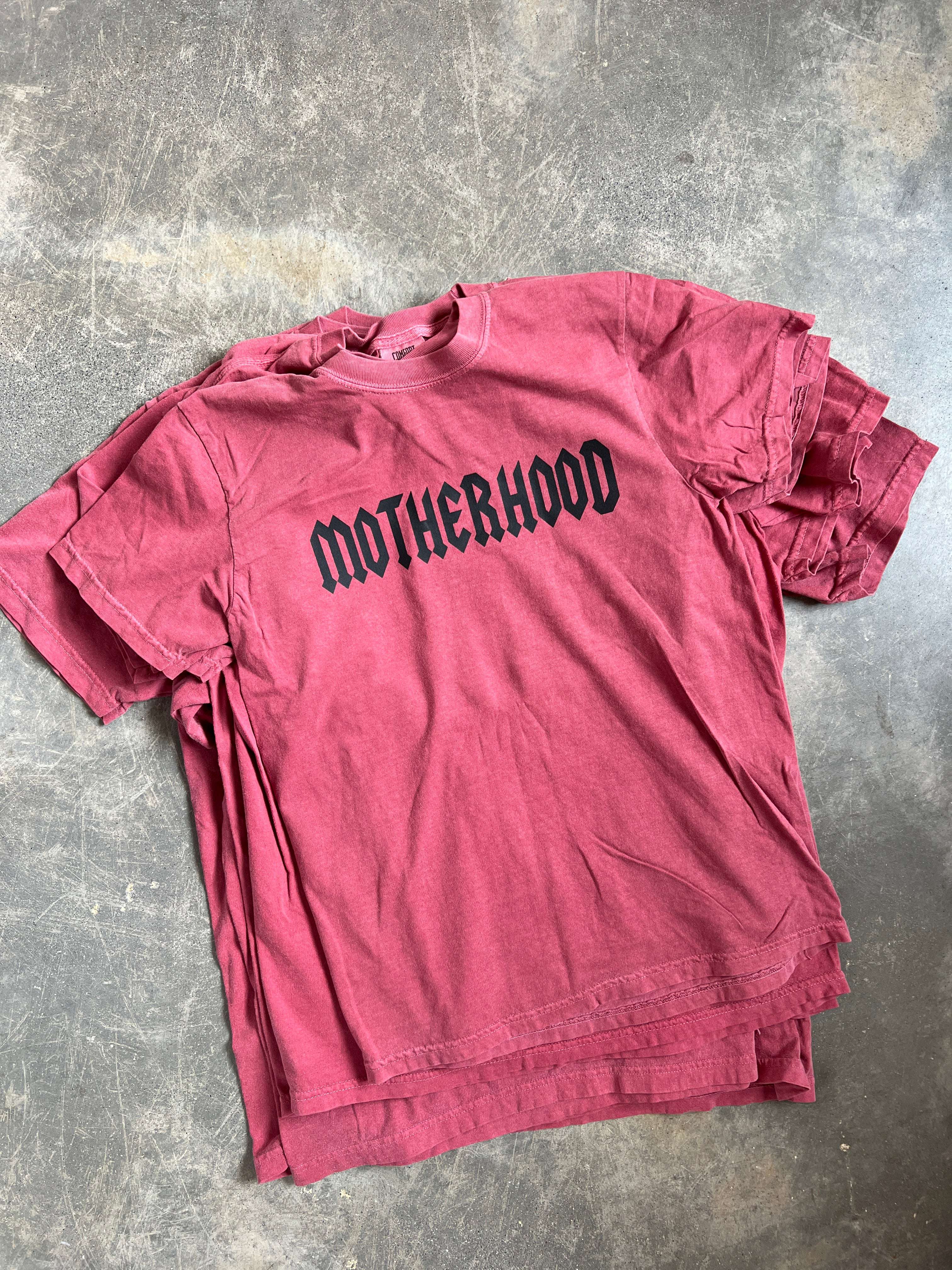 Motherhood Graphic Tee in burgundy color, featuring a bold black graphic print, showcasing a relaxed unisex fit.