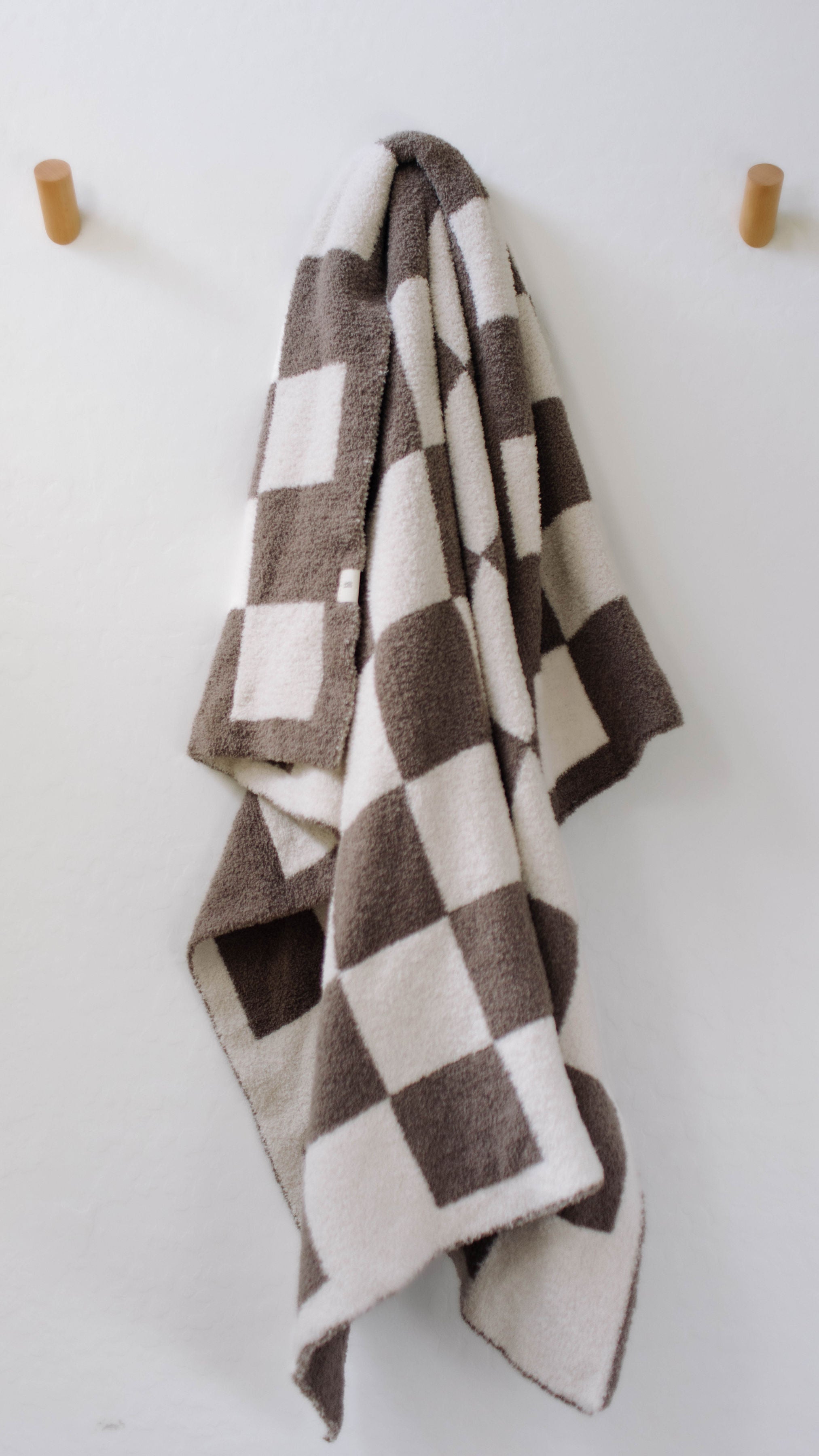 Mushroom checkerboard plush blanket hanging on a wall, perfect for cozy nursery decor.