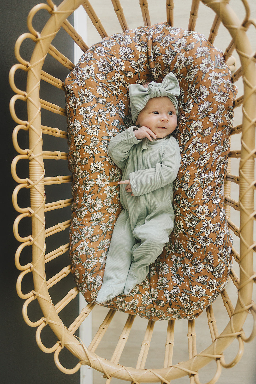 Baby wearing a sage organic ribbed head wrap and matching outfit in a cozy basket, showcasing organic baby head wrap style.