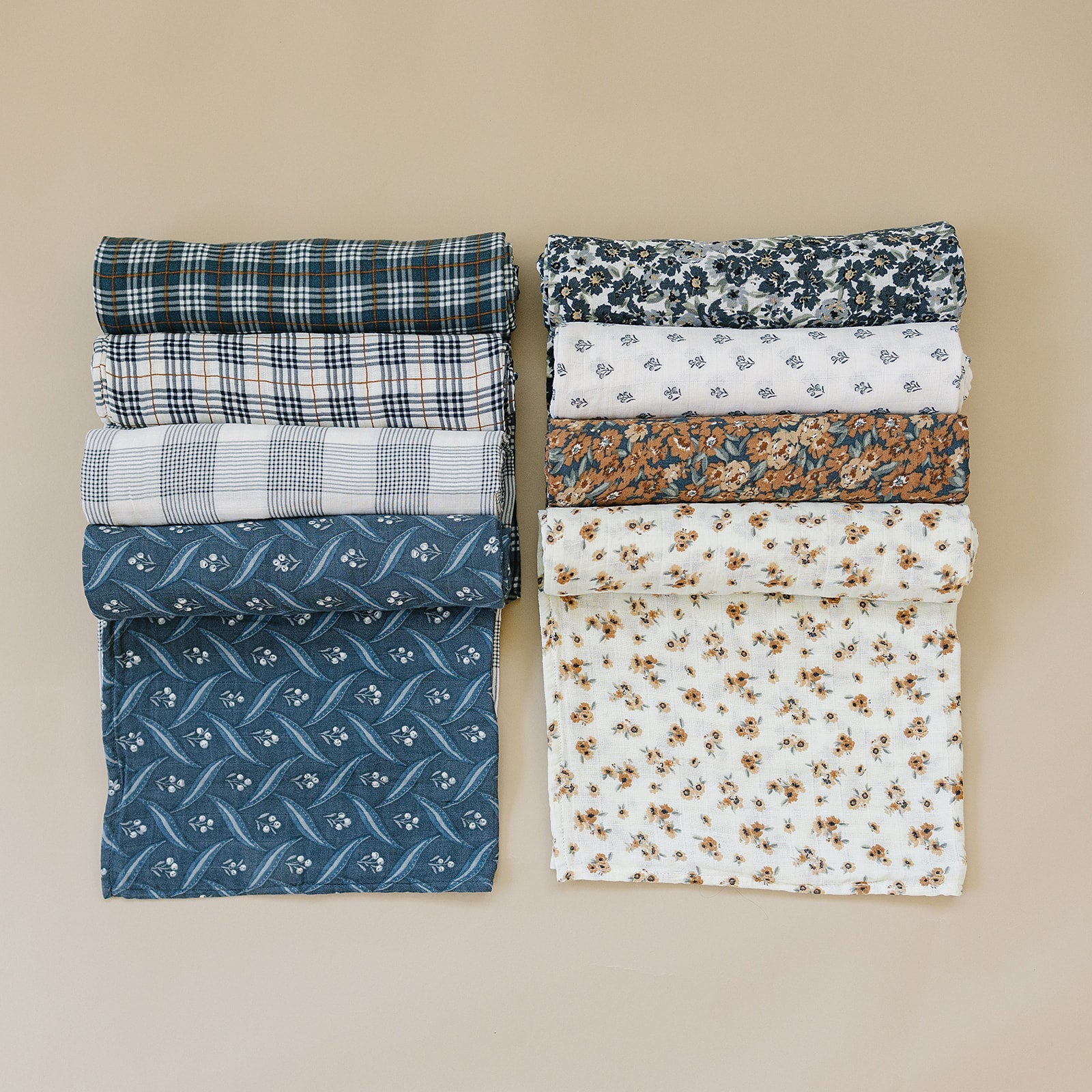 Variety of muslin fabrics including floral and plaid patterns, perfect for swaddles and crafting.