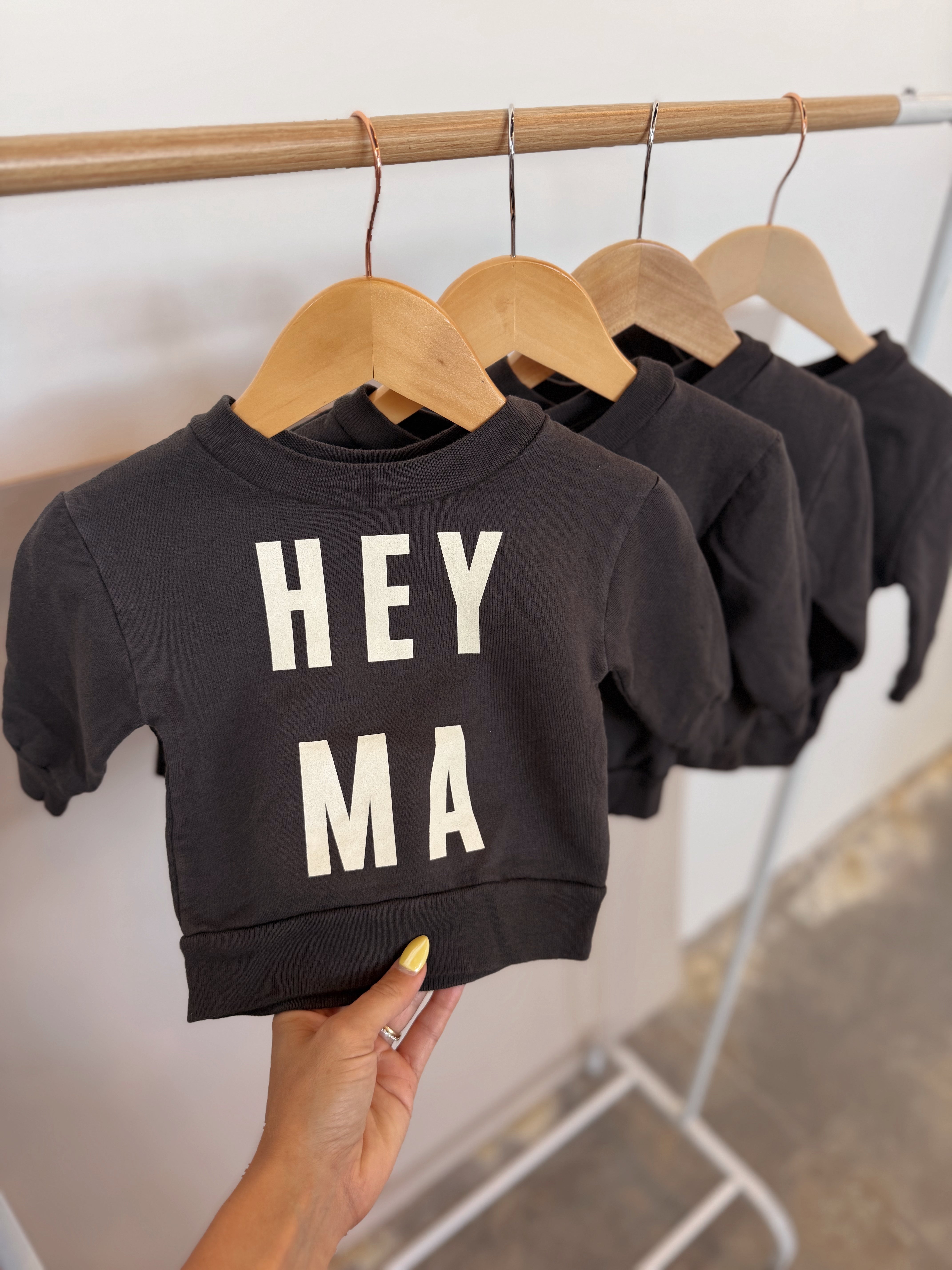 Hey Ma kids sweatshirt in black with relaxed fit, displayed on a hanger, showcasing minimalist design.