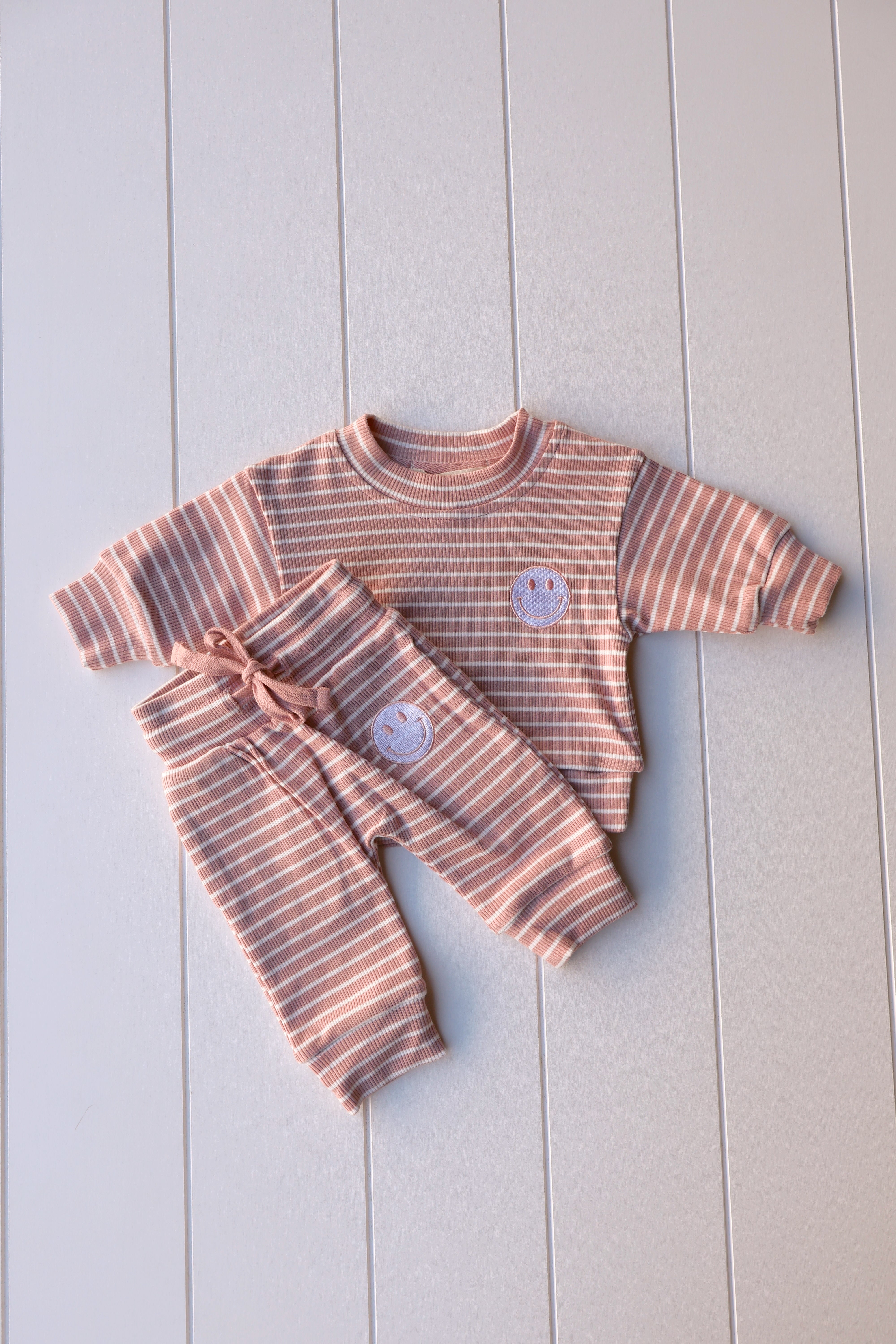 Smiley stripe set for toddlers featuring a cheerful smiley face tee and striped pants in soft pastel colors.