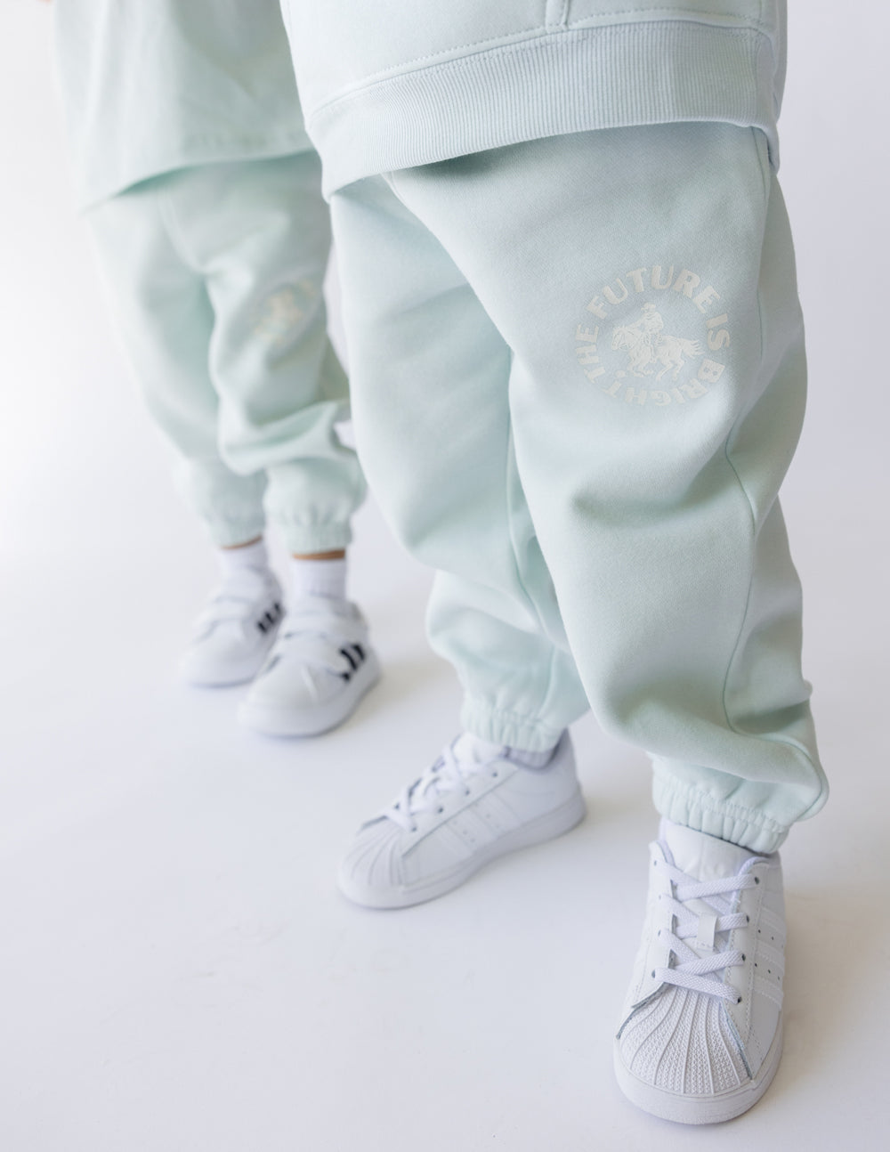 Kids wearing mint green The Future Is Bright sweatpants with white sneakers, showcasing comfort and style.