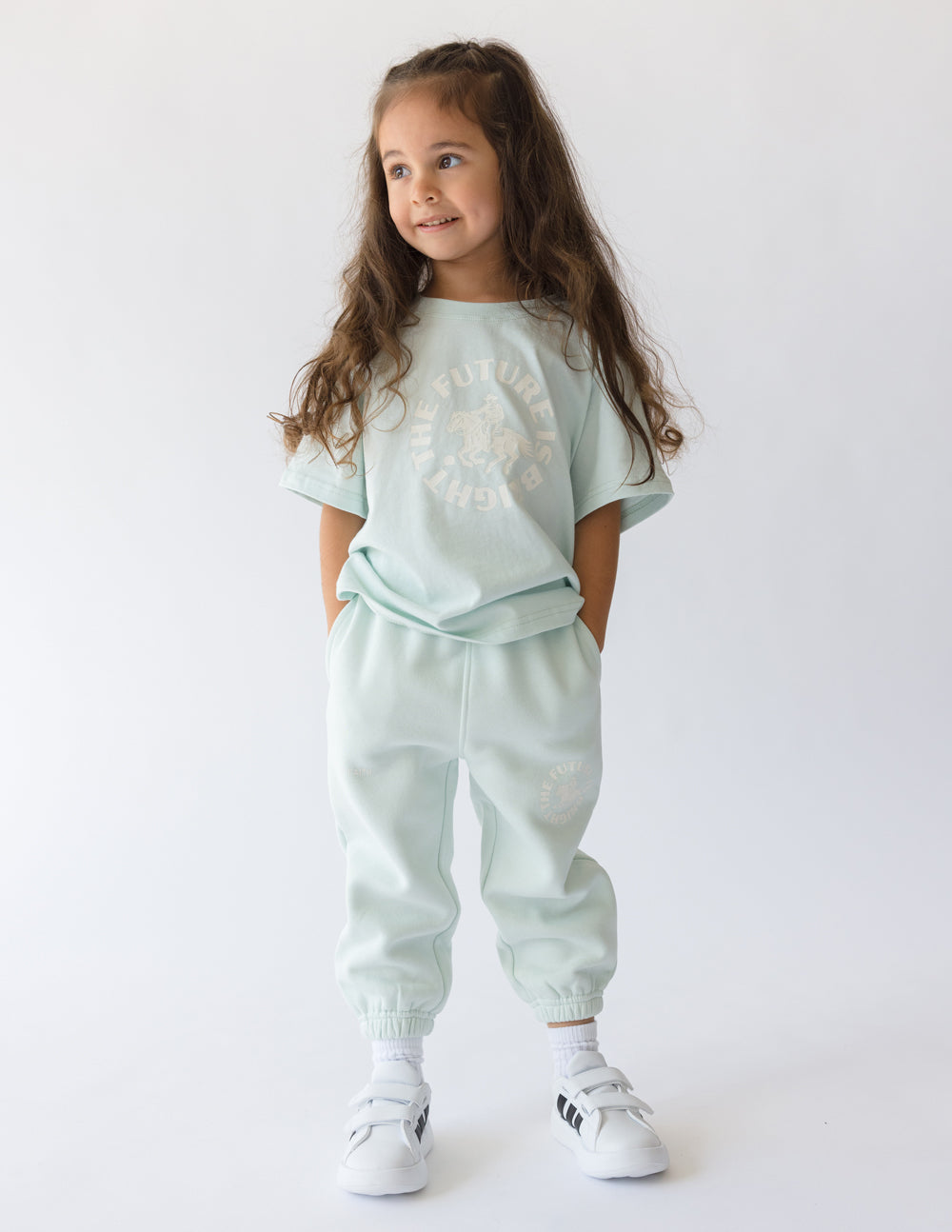 Smiling girl in mint green The Future Is Bright kids sweatpant and matching shirt, perfect for active play.