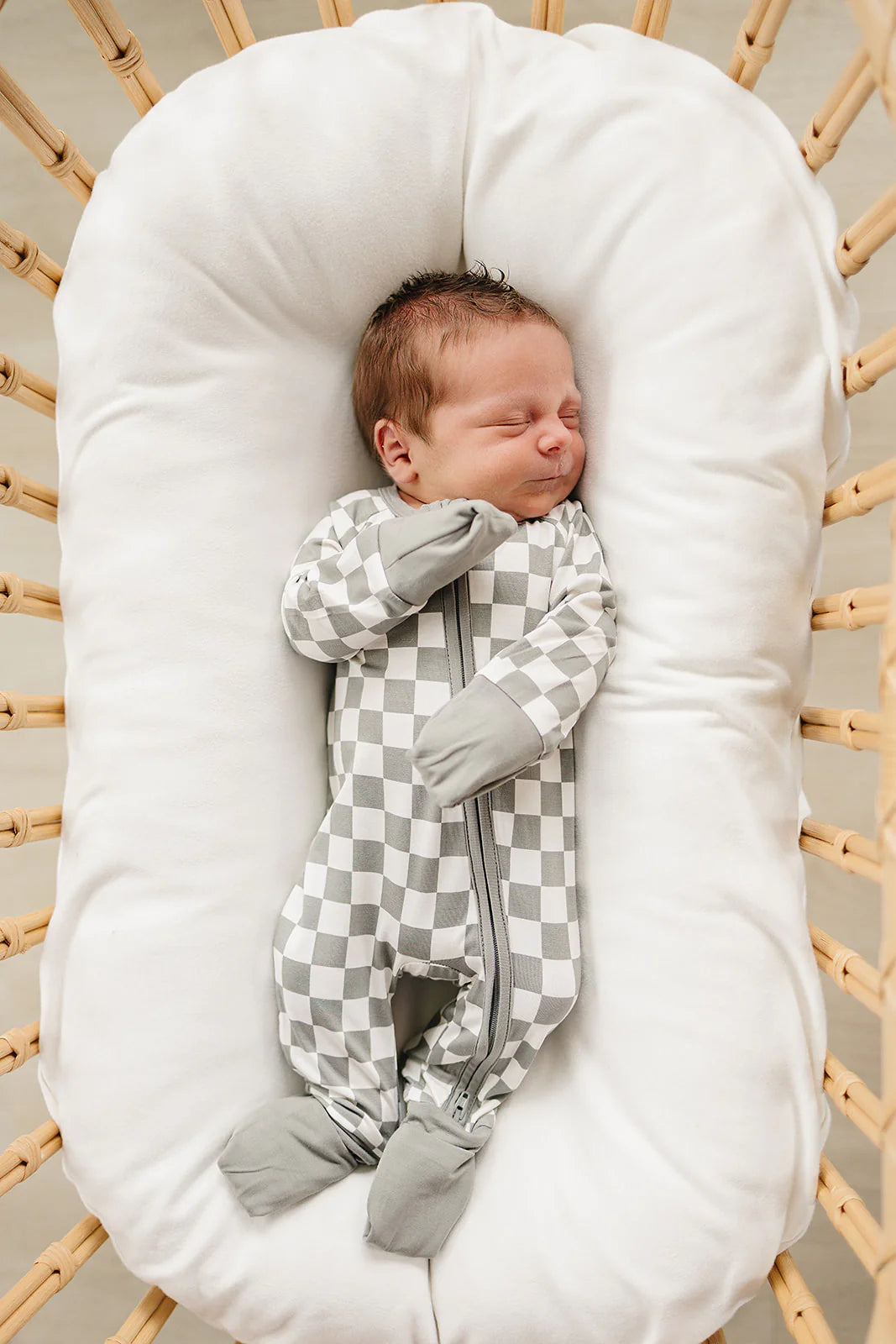 Baby sleeping in light green checkered bamboo zipper footed pajama, featuring cozy design and double zipper for easy changes.