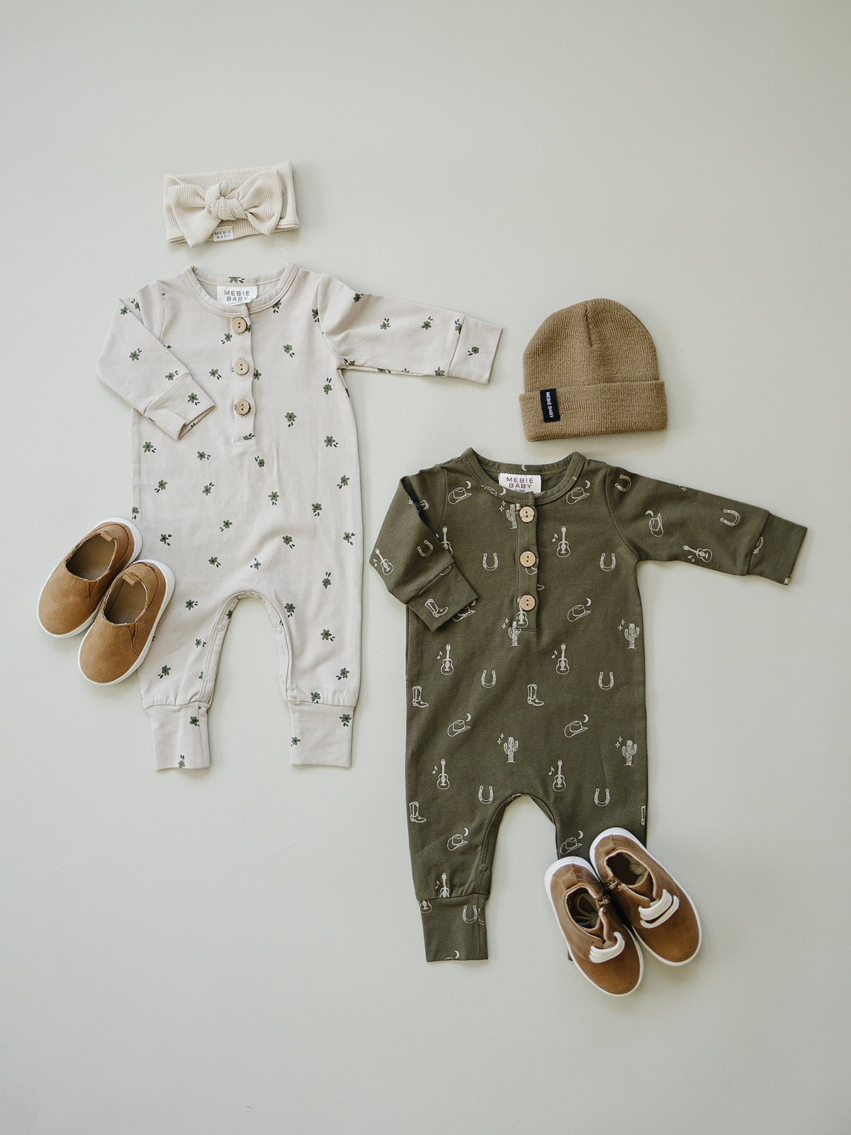 Two baby rompers in neutral colors with accessories, featuring patterns and buttons, perfect for stylish infants.