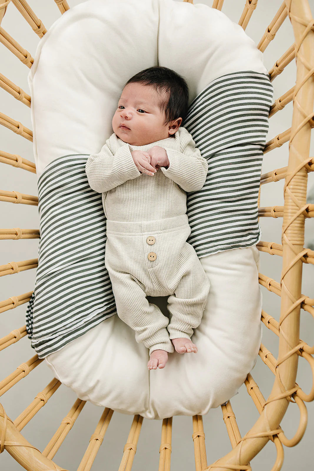 Waffle knit baby bodysuit set in heather grey, featuring a soft bodysuit and pants on a cozy bassinet.