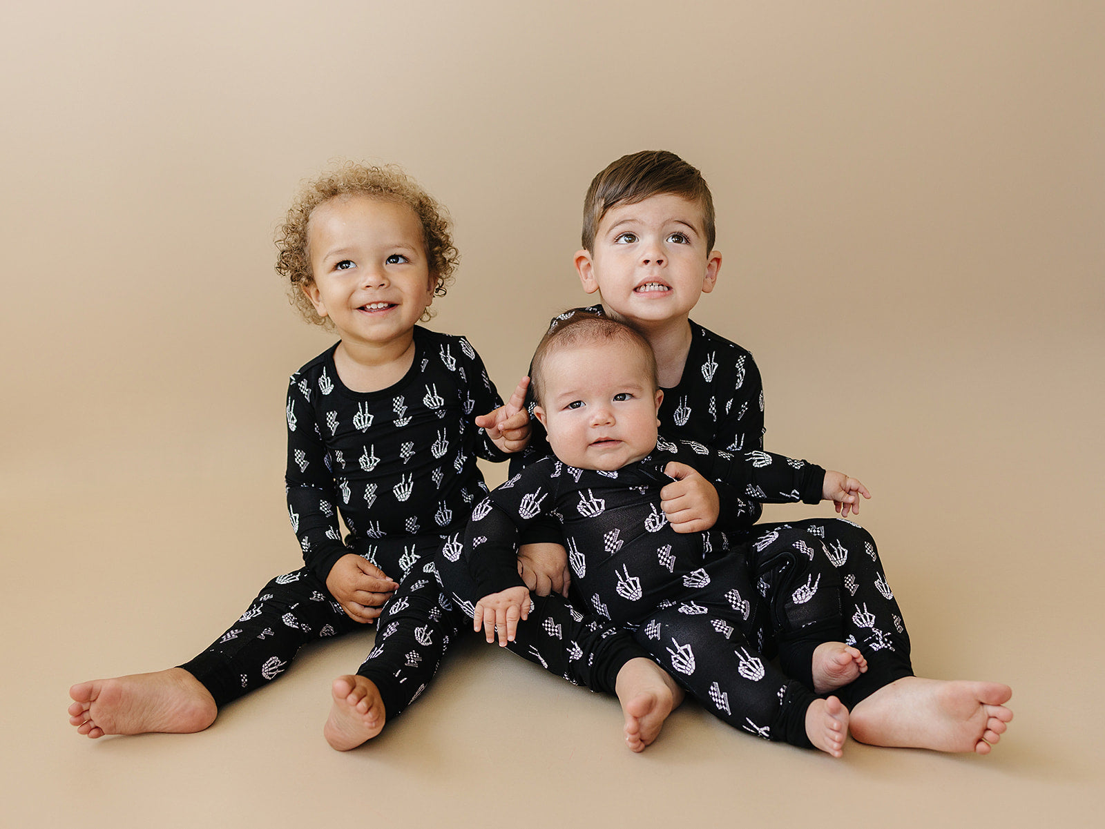 Bamboo Zip Romper Skelly Vibes on three kids, showcasing playful skeleton designs in cozy, ultra-soft fabric.