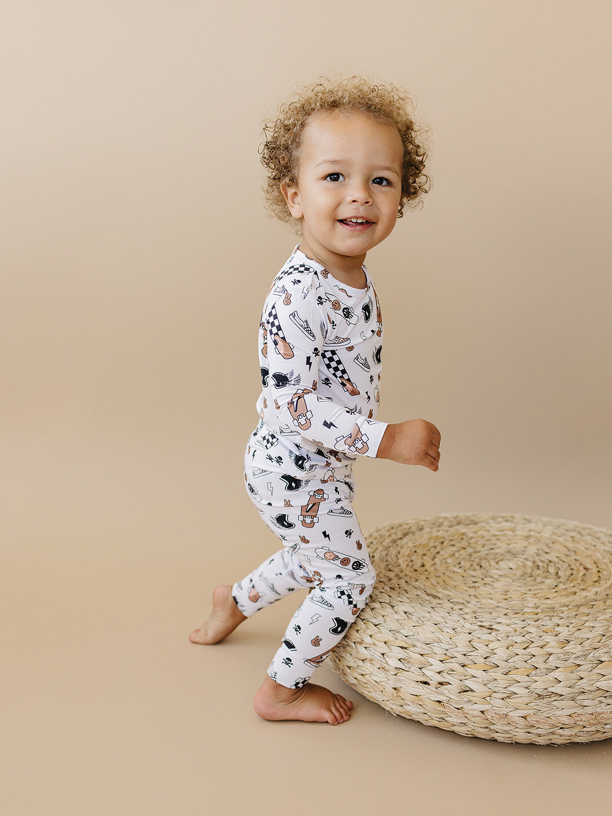 Toddler in Bamboo Two Piece Set Sk8er, featuring playful graphics of skateboards and sneakers, on a natural background.