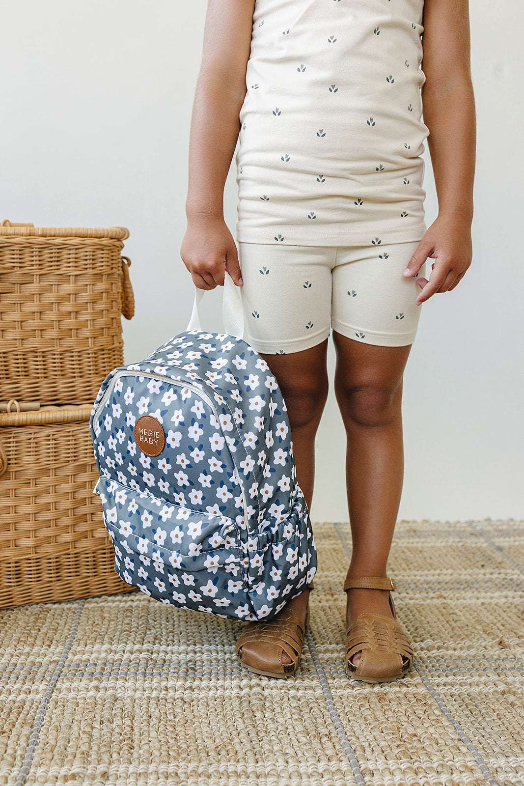 Child holding a floral kids mini backpack, perfect for daycare and outings, featuring stylish blue and white patterns.
