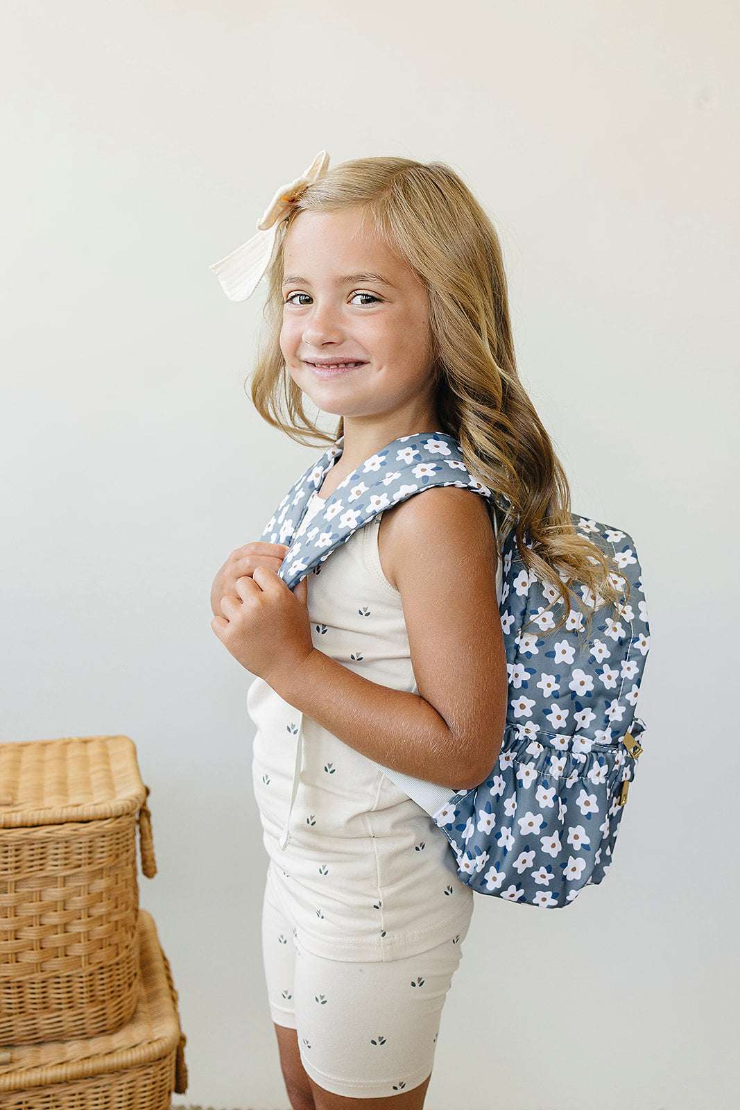 Cute girl wearing a kids mini backpack with a floral design, smiling and ready for preschool adventures.