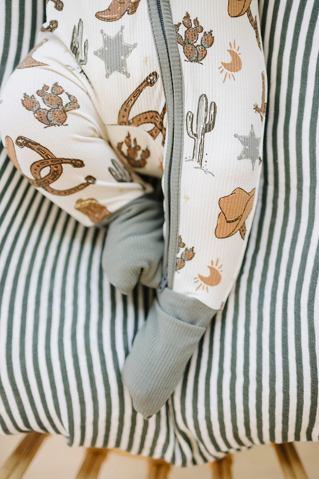 Outlaw cowboy bamboo zipper footie with cactus and star patterns, featuring fold-over cuffs for comfort.