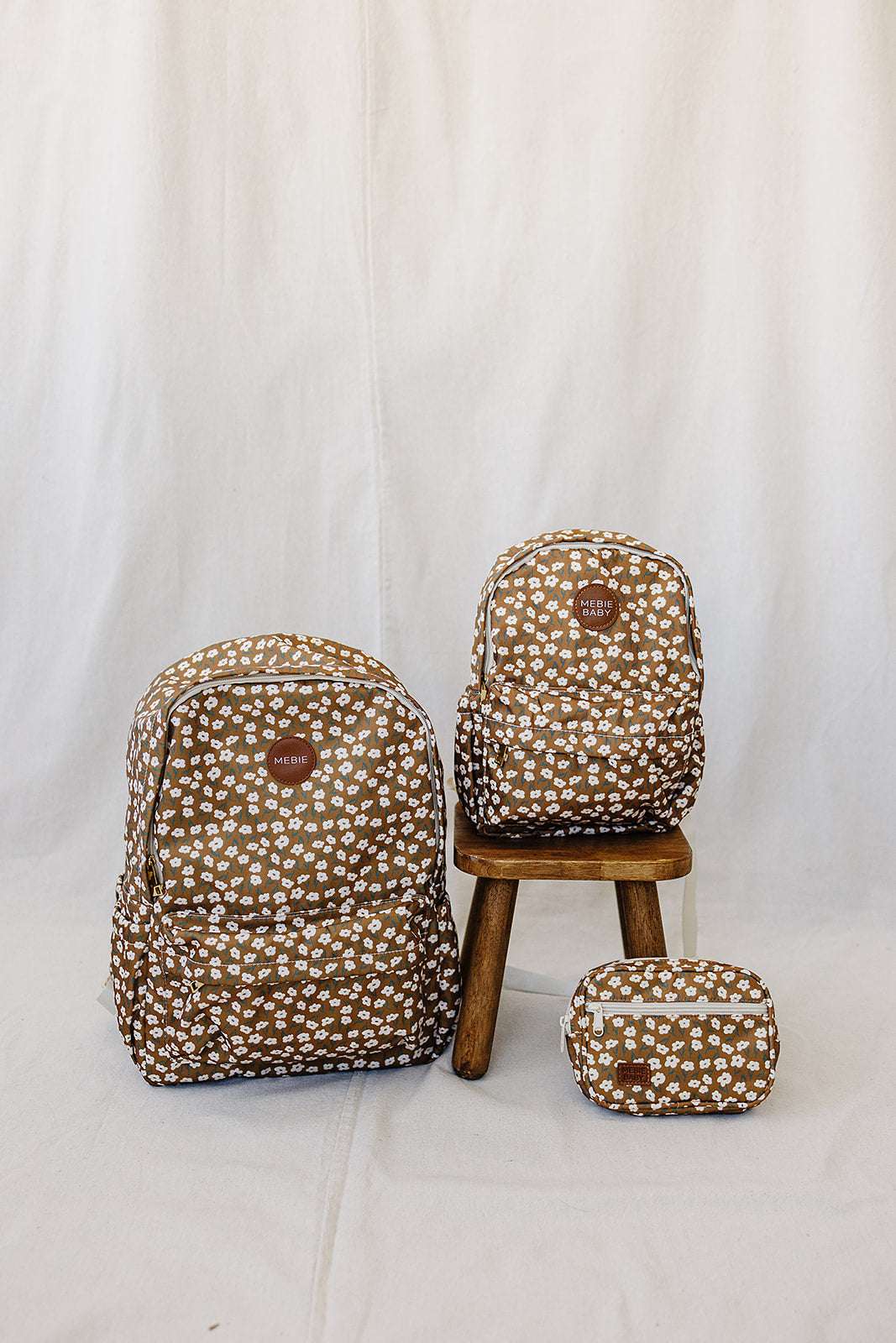 Kids school backpacks in brown floral pattern on a wooden stool, perfect for stylish and organized school days.
