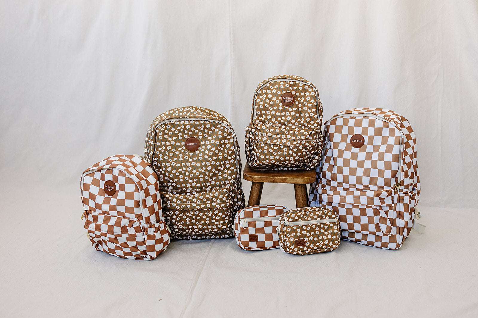 Cute kids' school backpacks with polka dot and checkered patterns displayed together on a chair.