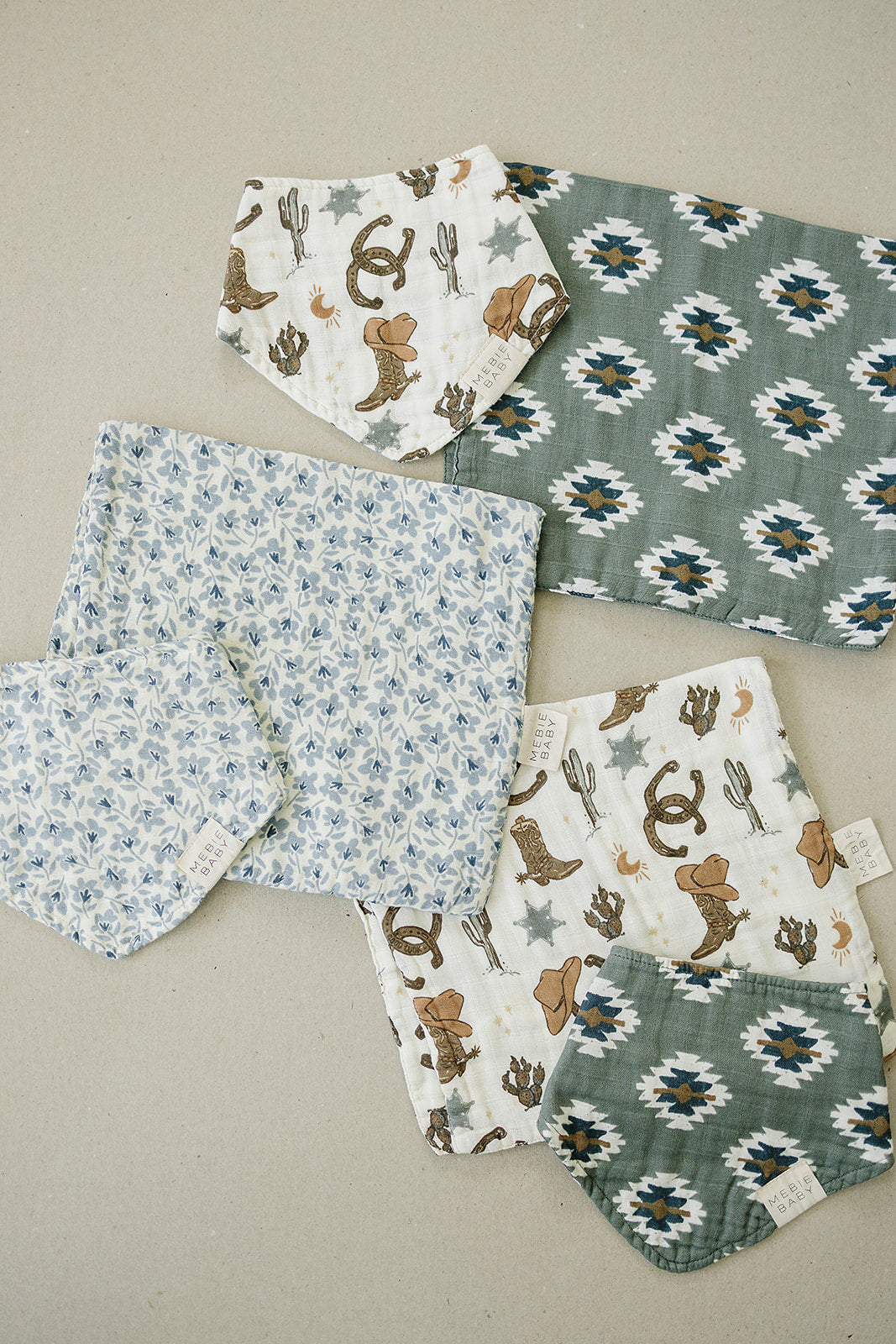 Collection of muslin bibs in playful prints, including floral and animal designs, perfect for baby's feeding and style.