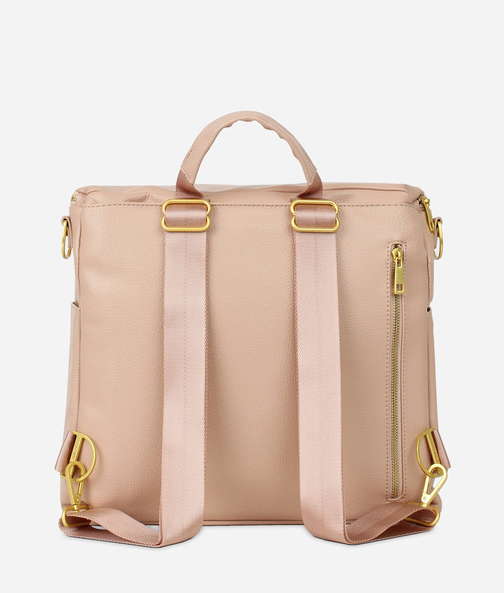 Back view of the Original Diaper Bag Backpack in warm blush faux leather with pink straps and gold accents.