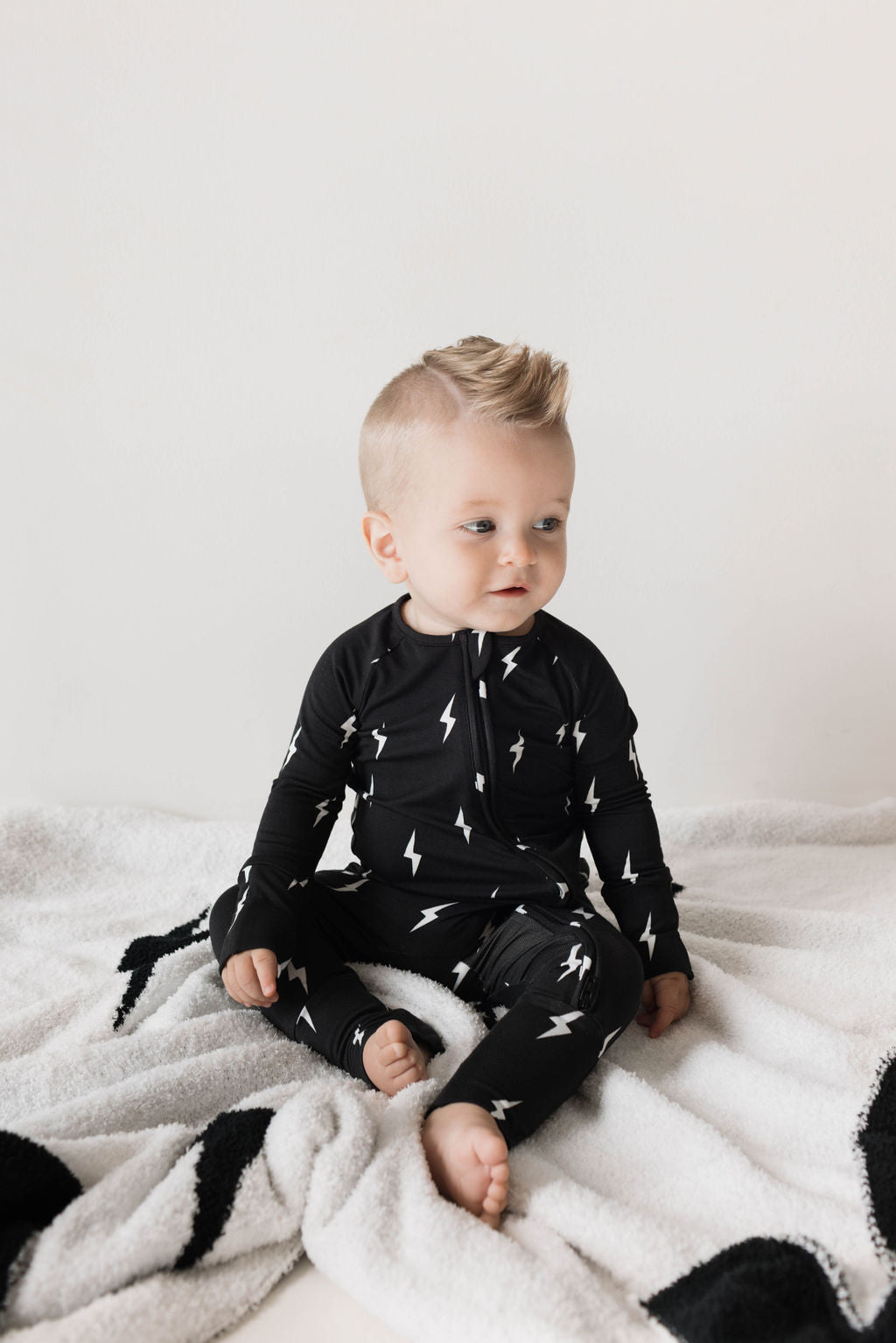 Baby wearing bamboo zip pajamas with lightning bolt print on a blanket