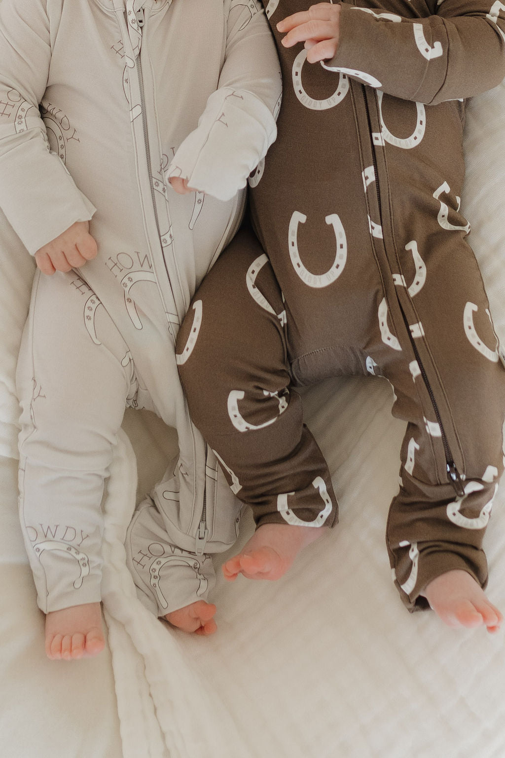 Bamboo zip pajamas for infants in beige and brown with cowboy-themed prints and horseshoes.