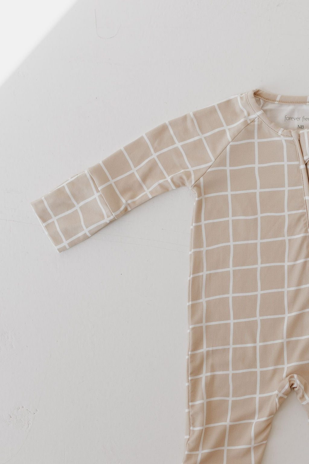 Bamboo zip pajamas for babies with a beige grid pattern, featuring a soft fabric for comfort and easy diaper changes.