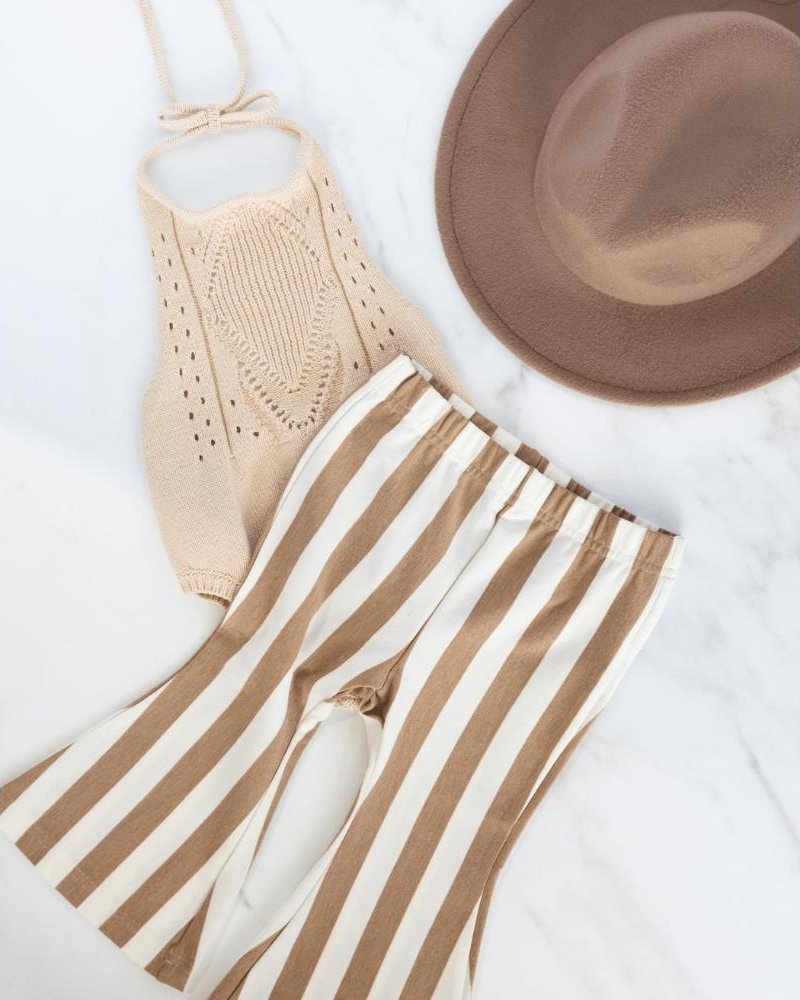 Tan striped bell bottom pants for kids with knit top and hat on marble surface.