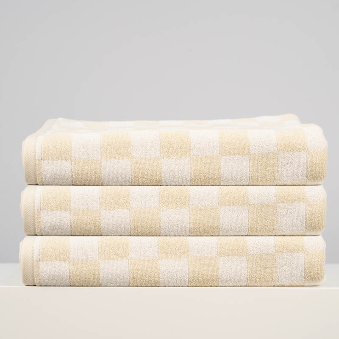 Stack of three soft checkered towels in beige and white, perfect for beach, bath, or pool use.