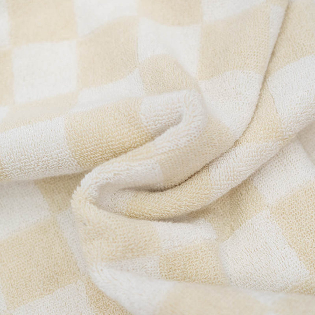 Soft checker beach and bath towel in beige and white, showcasing its absorbent texture and stylish design.