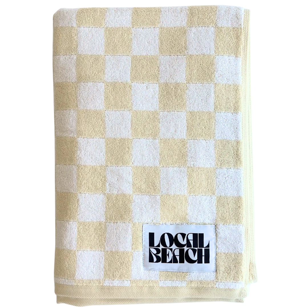 Checker beach towel in yellow and white, featuring 'LOCAL BEACH' label, perfect for summer outings.
