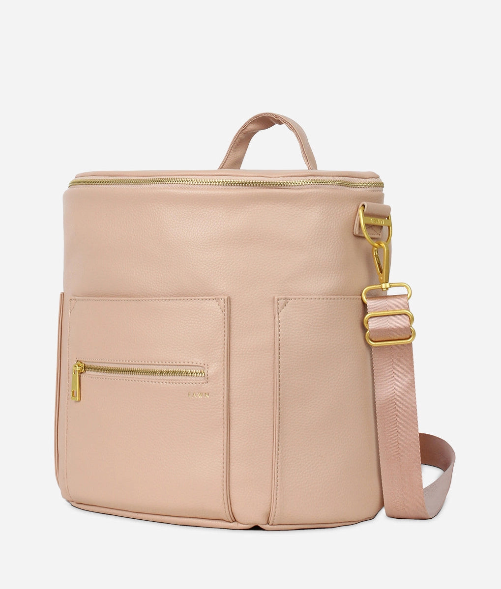 Original Diaper Bag Backpack in warm blush faux leather with gold accents and adjustable strap.