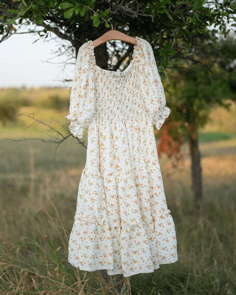 Katherine Dress in yellow floral pattern hanging on a tree, perfect for matching summer outfits for all ages.
