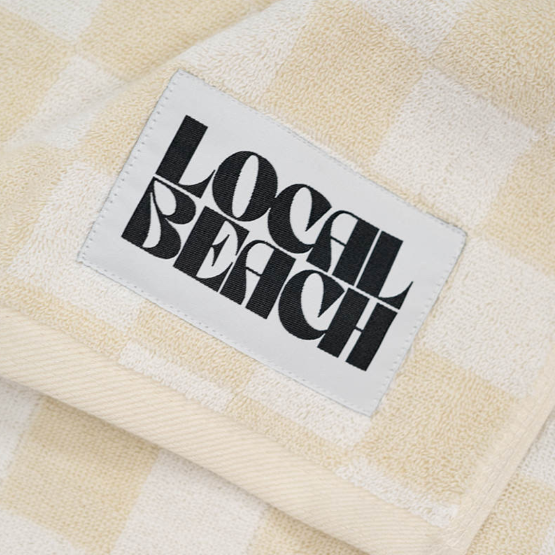 Soft checkered towel featuring 'Local Beach' label, perfect for beach days and stylish lounging.