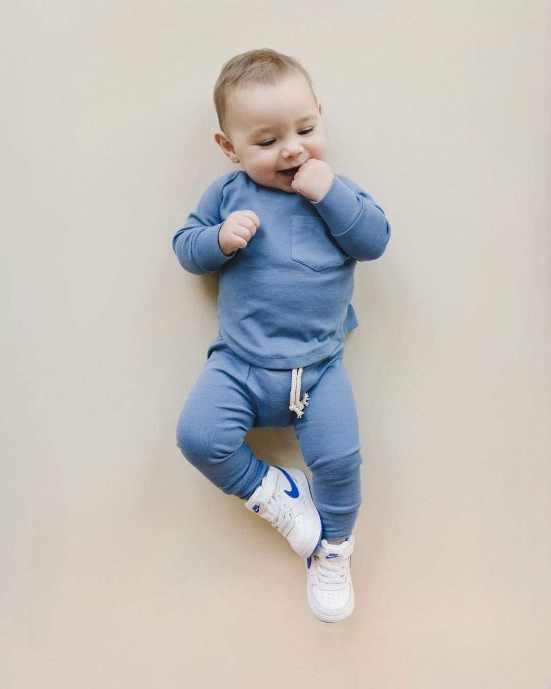 Baby wearing an ocean blue lounge set, featuring a cozy top and matching bottoms, styled with white sneakers.