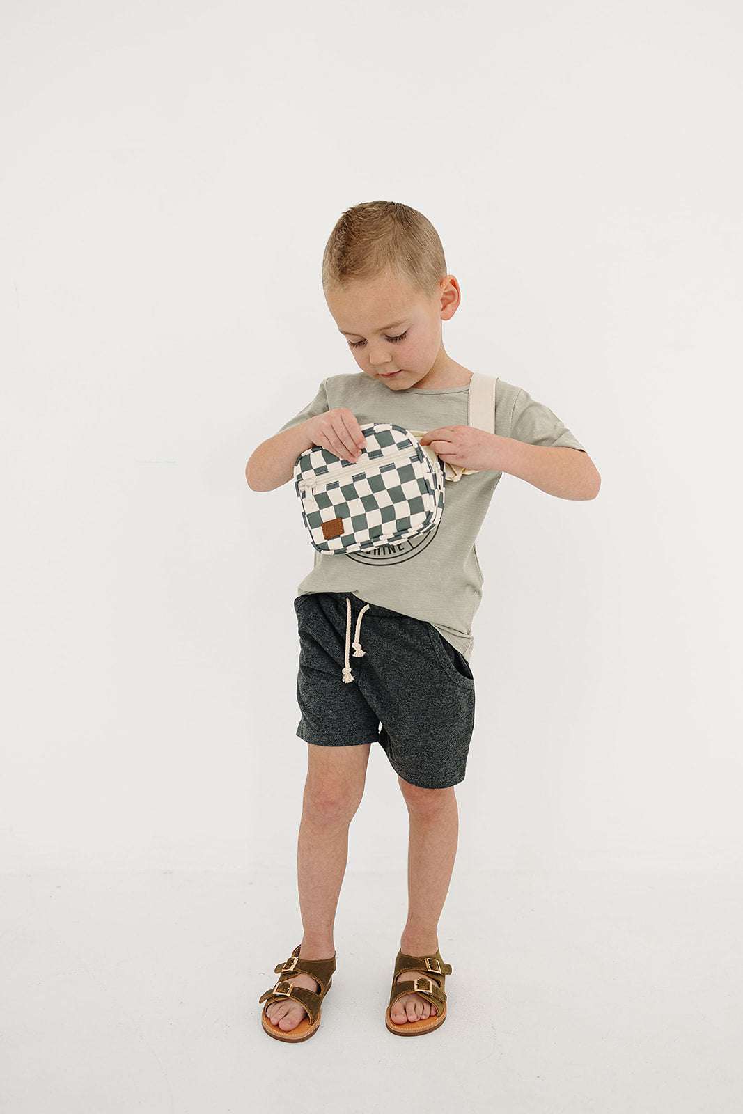 Child wearing a green checkered mini fanny pack, featuring a playful design and hands-free style.