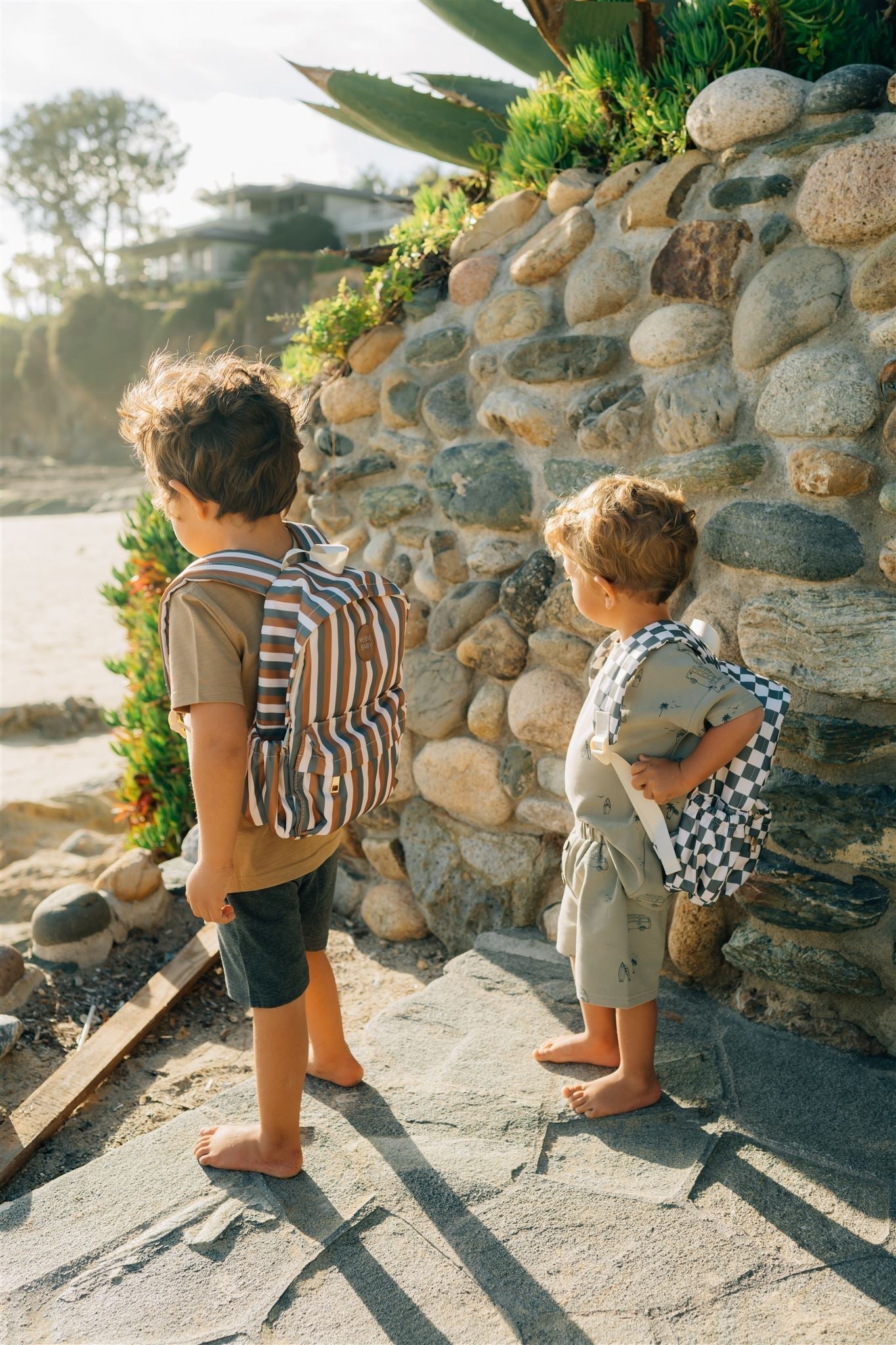 Two kids exploring outdoors with stylish mini backpacks, enjoying their summer adventures by the water.