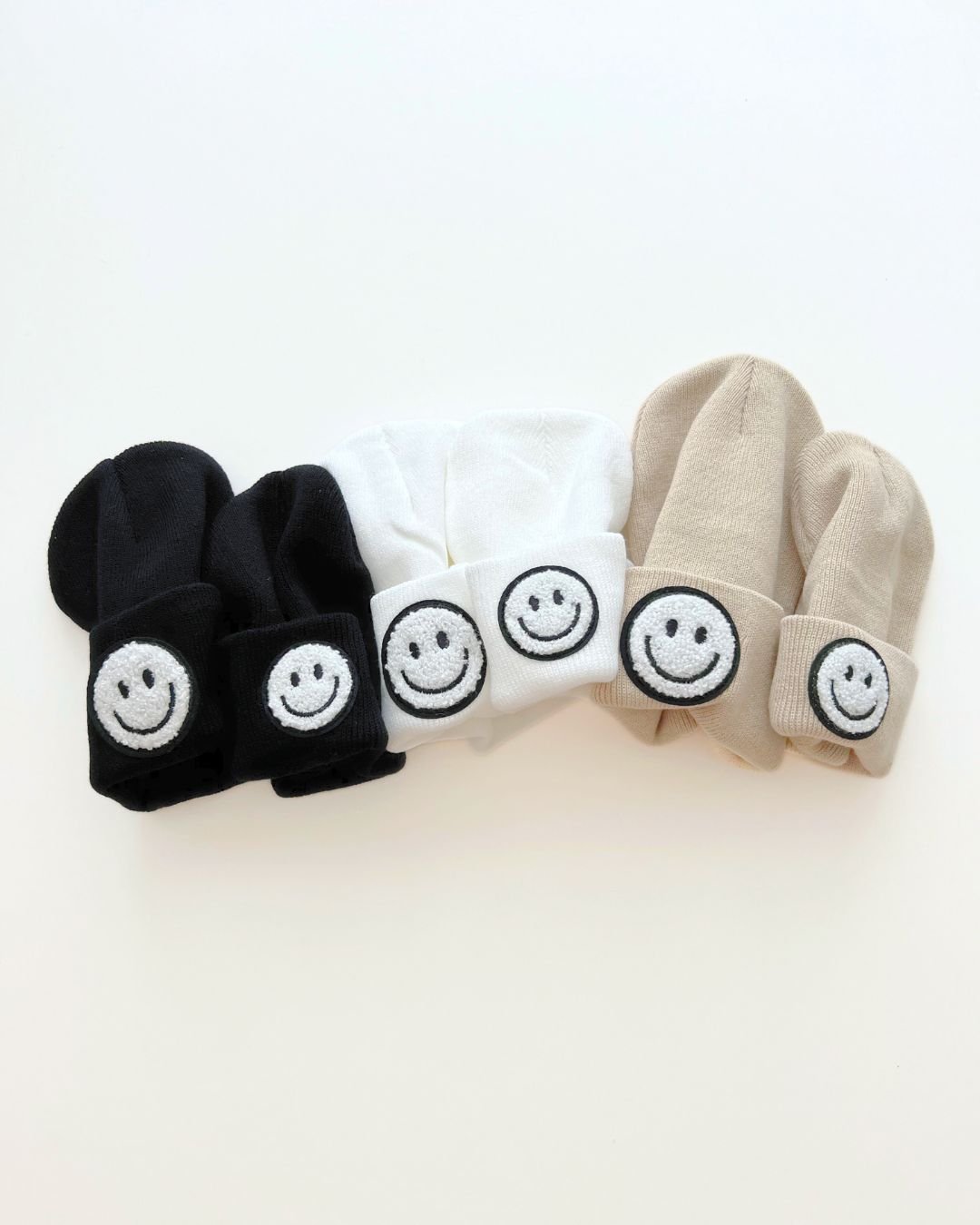 Smiley Beanie collection in black, white, and beige showcasing cheerful smiley faces for stylish warmth.