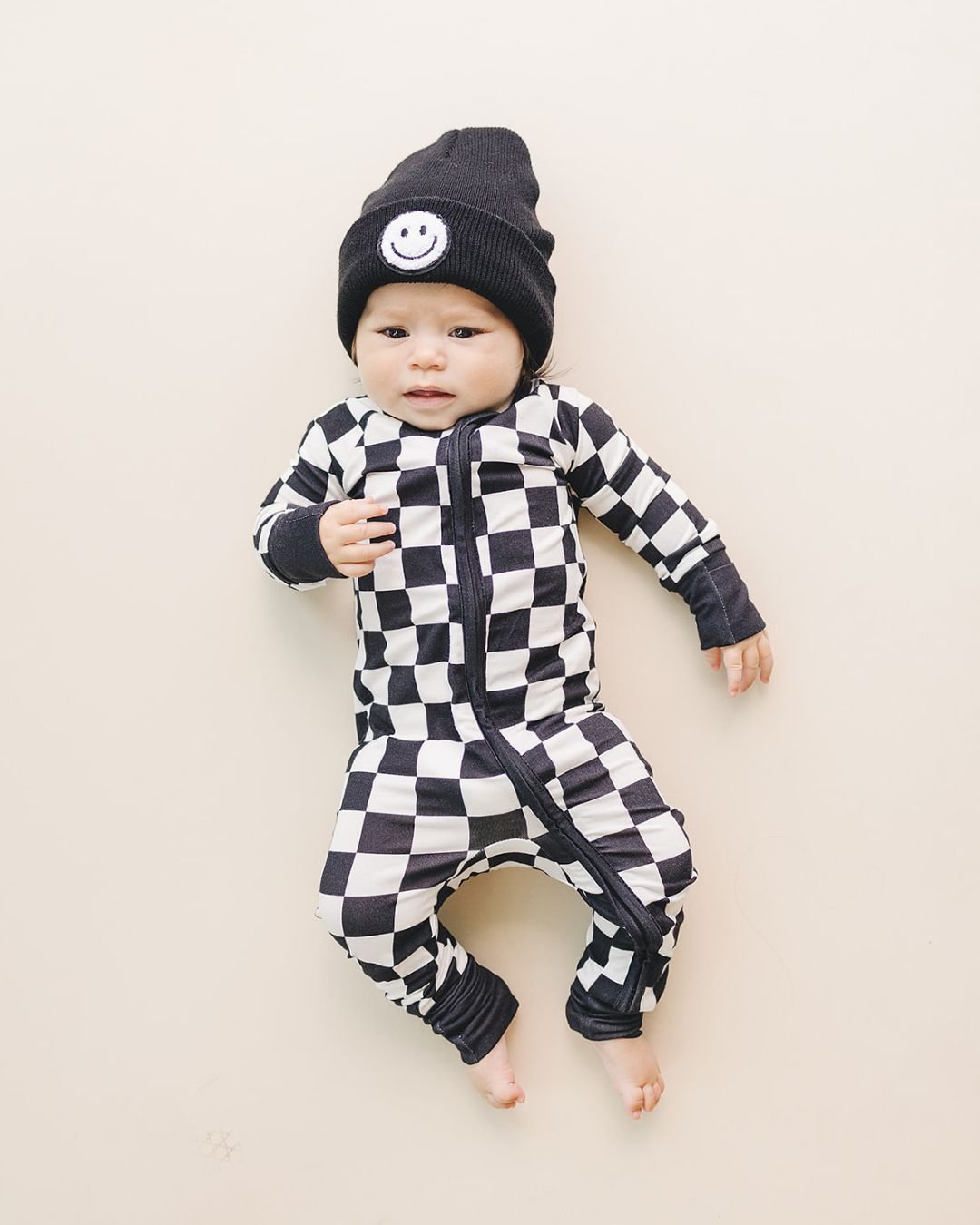 Baby wearing a black Smiley Beanie with a checkered jumpsuit, showcasing cozy and stylish outfit options for little ones.